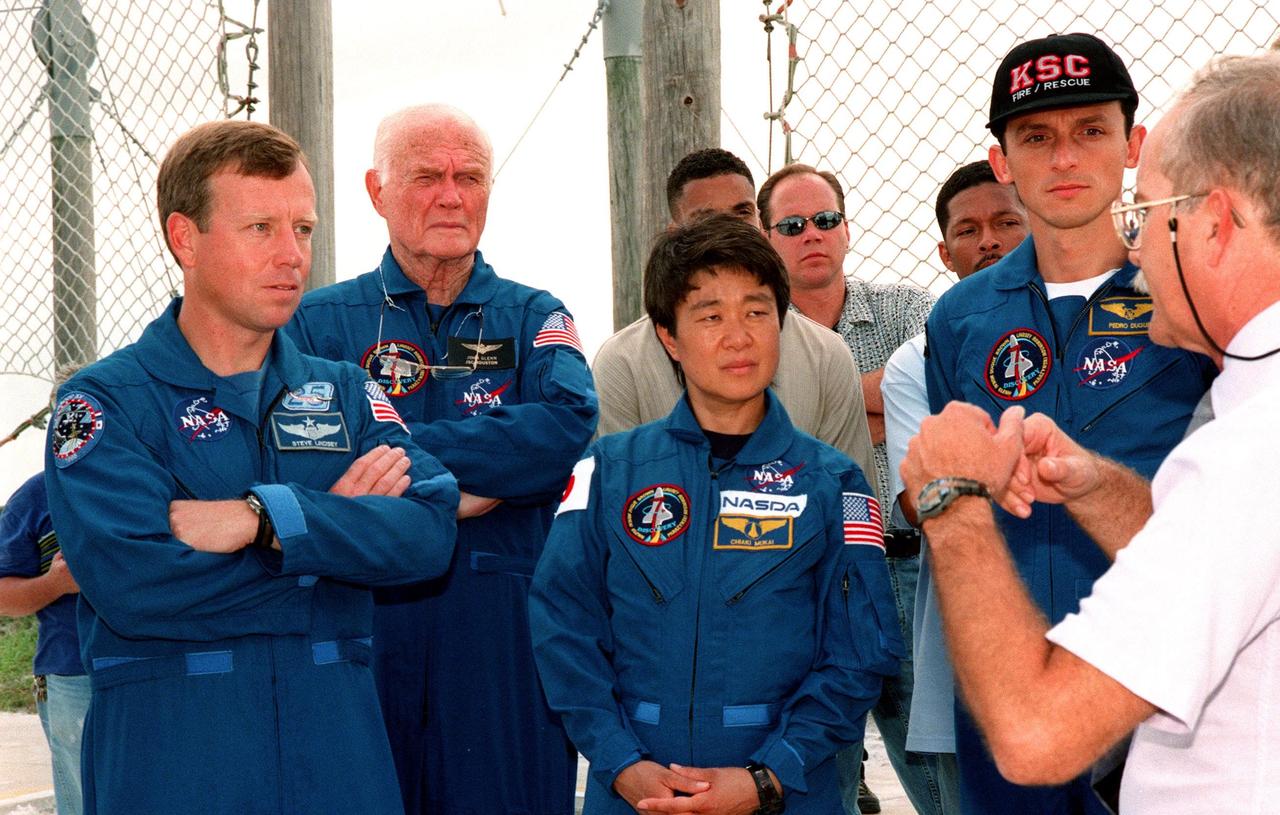 At Launch Pad 39-B, a Safety Egress trainer explains the use of the slidewire basket system for emergency egress before launch to STS-95 crew members (left to right) Pilot Steven W. Lindsey, Payload Specialists John H. Glenn Jr., senator from Ohio, and Chiaki Mukai, representing the National Space Development Agency of Japan (NASDA), and Mission Specialist Pedro Duque of Spain, representing the European Space Agency. The STS-95 crew are at KSC to participate in a Terminal Countdown Demonstration Test (TCDT) which includes mission familiarization activities, emergency egress training, and a simulated main engine cut-off exercise. Other members of the crew not shown are Mission Specialist Scott E. Parazynski, Mission Commander Curtis L. Brown, and Mission Specialist Stephen K. Robinson. The STS-95 mission, targeted for liftoff on Oct. 29, includes research payloads such as the Spartan solar-observing deployable spacecraft, the Hubble Space Telescope Orbital Systems Test Platform, the International Extreme Ultraviolet Hitchhiker, as well as the SPACEHAB single module with experiments on space flight and the aging process. Following the TCDT, the crew will be returning to Houston for final flight preparations