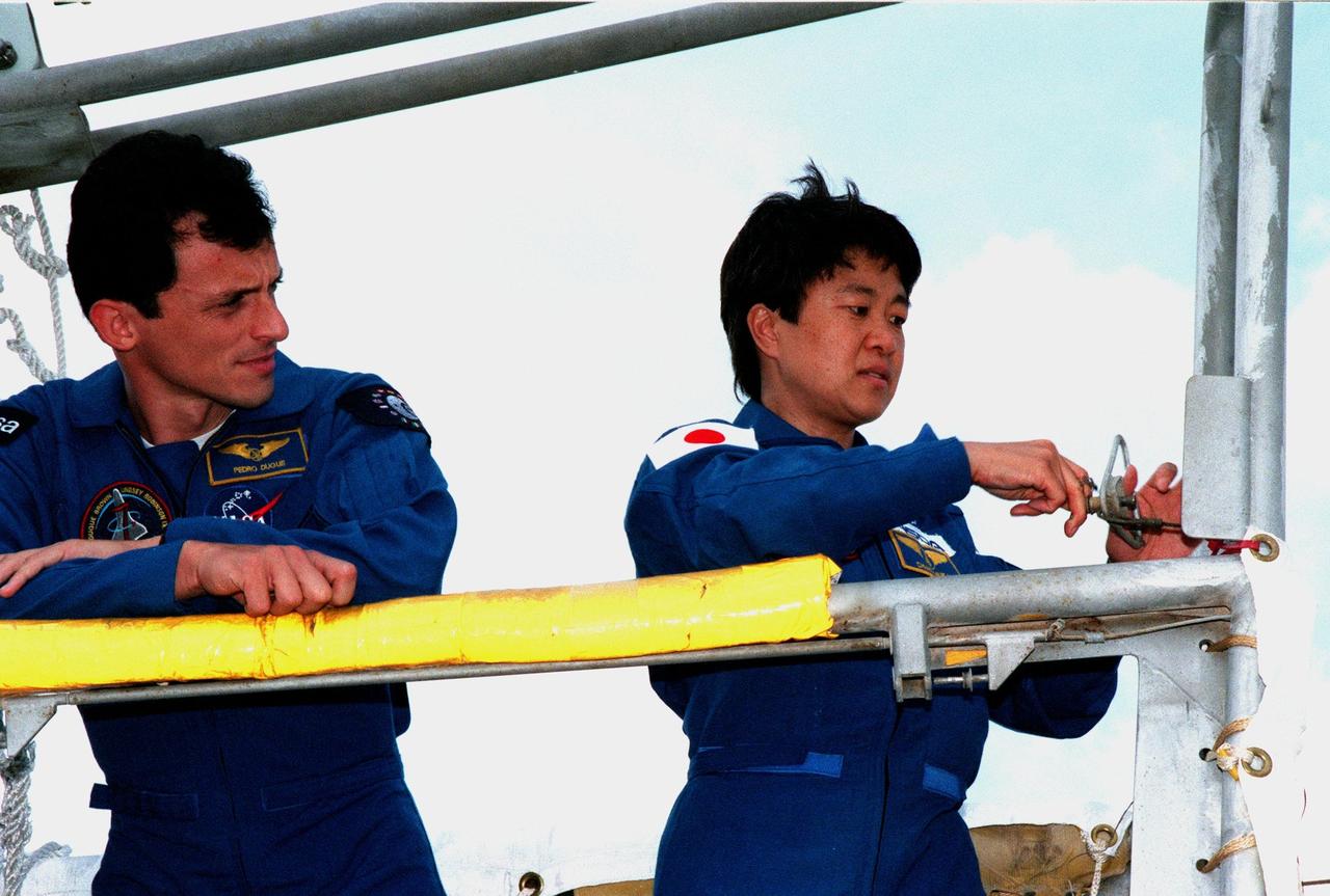 At Launch Pad 39-B, STS-95 Payload Specialist Chiaki Mukai (right) pulls the pin that releases the gate for the slidewire basket, part of the emergency egress system on the pad, while Mission Specialist Pedro Duque of Spain watches. Mukai represents the National Space Development Agency of Japan (NASDA), and Duque the European Space Agency (ESA). The STS-95 crew are at KSC to participate in a Terminal Countdown Demonstration Test (TCDT) which includes mission familiarization activities, emergency egress training, and a simulated main engine cut-off exercise. Other STS-95 crew members are Mission Specialist Stephen K. Robinson, Mission Commander Curtis L. Brown, Pilot Steven W. Lindsey, Payload Specialists John H. Glenn Jr., senator from Ohio, and Mission Specialist Scott E. Parazynski. The STS-95 mission, targeted for liftoff on Oct. 29, includes research payloads such as the Spartan solar-observing deployable spacecraft, the Hubble Space Telescope Orbital Systems Test Platform, the International Extreme Ultraviolet Hitchhiker, as well as the SPACEHAB single module with experiments on space flight and the aging process. Following the TCDT, the crew will be returning to Houston for final flight preparations