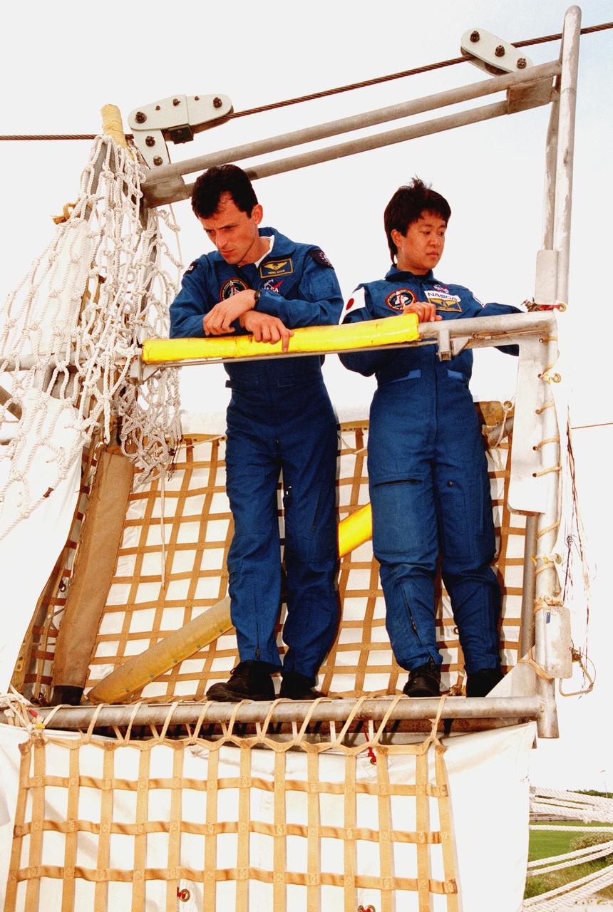 At Launch Pad 39-B, STS-95 Mission Specialist Pedro Duque of Spain (left) and Payload Specialist Chiaki Mukai look over the gate for the slidewire basket, part of the emergency egress system on the pad. Mukai represents the National Space Development Agency of Japan (NASDA), and Duque the European Space Agency (ESA). The STS-95 crew are at KSC to participate in a Terminal Countdown Demonstration Test (TCDT) which includes mission familiarization activities, emergency egress training, and a simulated main engine cut-off exercise. Other STS-95 crew members are Mission Specialist Stephen K. Robinson, Mission Commander Curtis L. Brown, Pilot Steven W. Lindsey, Payload Specialists John H. Glenn Jr., senator from Ohio, and Mission Specialist Scott E. Parazynski. The STS-95 mission, targeted for liftoff on Oct. 29, includes research payloads such as the Spartan solar-observing deployable spacecraft, the Hubble Space Telescope Orbital Systems Test Platform, the International Extreme Ultraviolet Hitchhiker, as well as the SPACEHAB single module with experiments on space flight and the aging process. Following the TCDT, the crew will be returning to Houston for final flight preparations