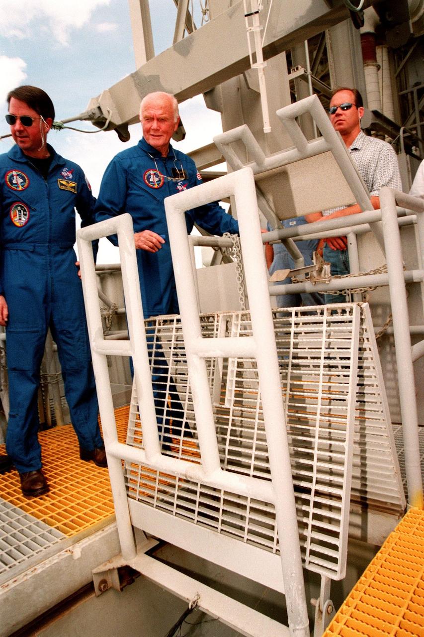 STS-95 Payload Specialist John H. Glenn Jr. (right) releases the slidewire basket, an emergency egress vehicle, at the 195-foot level of Launch Pad 39-B, while Mission Specialist Stephen K. Robinson (left) watches. The STS-95 crew are at KSC to participate in a Terminal Countdown Demonstration Test (TCDT) which includes mission familiarization activities, emergency egress training, and a simulated main engine cut-off exercise. Other crew members are Mission Specialist Scott E. Parazynski, Mission Specialist Pedro Duque of Spain, representing the European Space Agency (ESA), Pilot Steven W. Lindsey, Payload Specialist Chiaki Mukai, representing the National Space Development Agency of Japan (NASDA), and Mission Commander Curtis L. Brown. The STS-95 mission, targeted for liftoff on Oct. 29, includes research payloads such as the Spartan solar-observing deployable spacecraft, the Hubble Space Telescope Orbital Systems Test Platform, the International Extreme Ultraviolet Hitchhiker, as well as the SPACEHAB single module with experiments on space flight and the aging process. Following the TCDT, the crew will be returning to Houston for final flight preparations