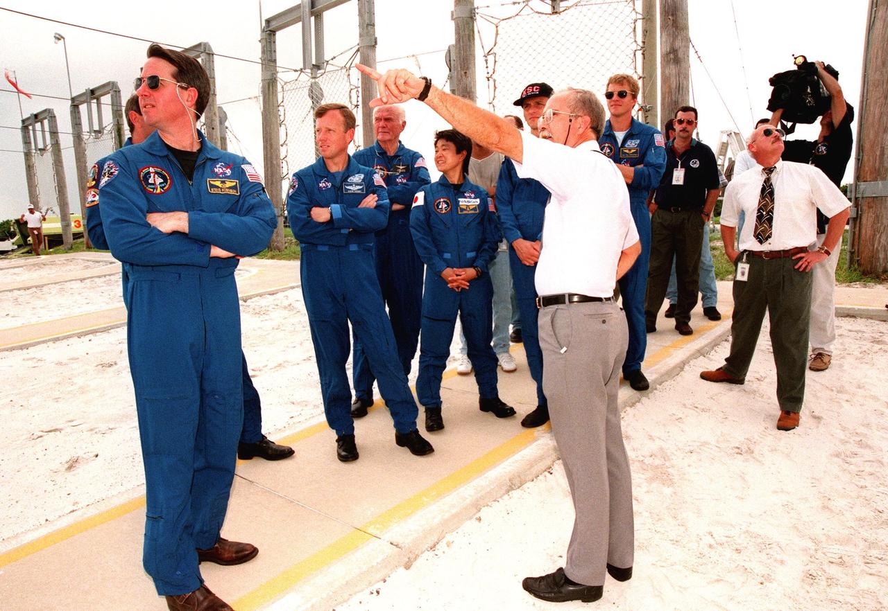 On Launch Pad 39-B, a Safety Egress trainer points out to the STS-95 crew the path the slidewire baskets, emergency egress vehicles, will take if the crew needs to use them before launch. Watching are (left to right) Mission Specialist Stephen K. Robinson, Mission Commander Curtis L. Brown (partially hidden behind Robinson), Pilot Steven W. Lindsey, Payload Specialists John H. Glenn Jr., senator from Ohio, and Chiaki Mukai, representing the National Space Development Agency of Japan (NASDA), Mission Specialist Pedro Duque of Spain, representing the European Space Agency (ESA), and Mission Specialist Scott E. Parazynski. The STS-95 crew are at KSC to participate in a Terminal Countdown Demonstration Test (TCDT) which includes mission familiarization activities, emergency egress training, and a simulated main engine cut-off exercise. The STS-95 mission, targeted for liftoff on Oct. 29, includes research payloads such as the Spartan solar-observing deployable spacecraft, the Hubble Space Telescope Orbital Systems Test Platform, the International Extreme Ultraviolet Hitchhiker, as well as the SPACEHAB single module with experiments on space flight and the aging process. Following the TCDT, the crew will be returning to Houston for final flight preparations
