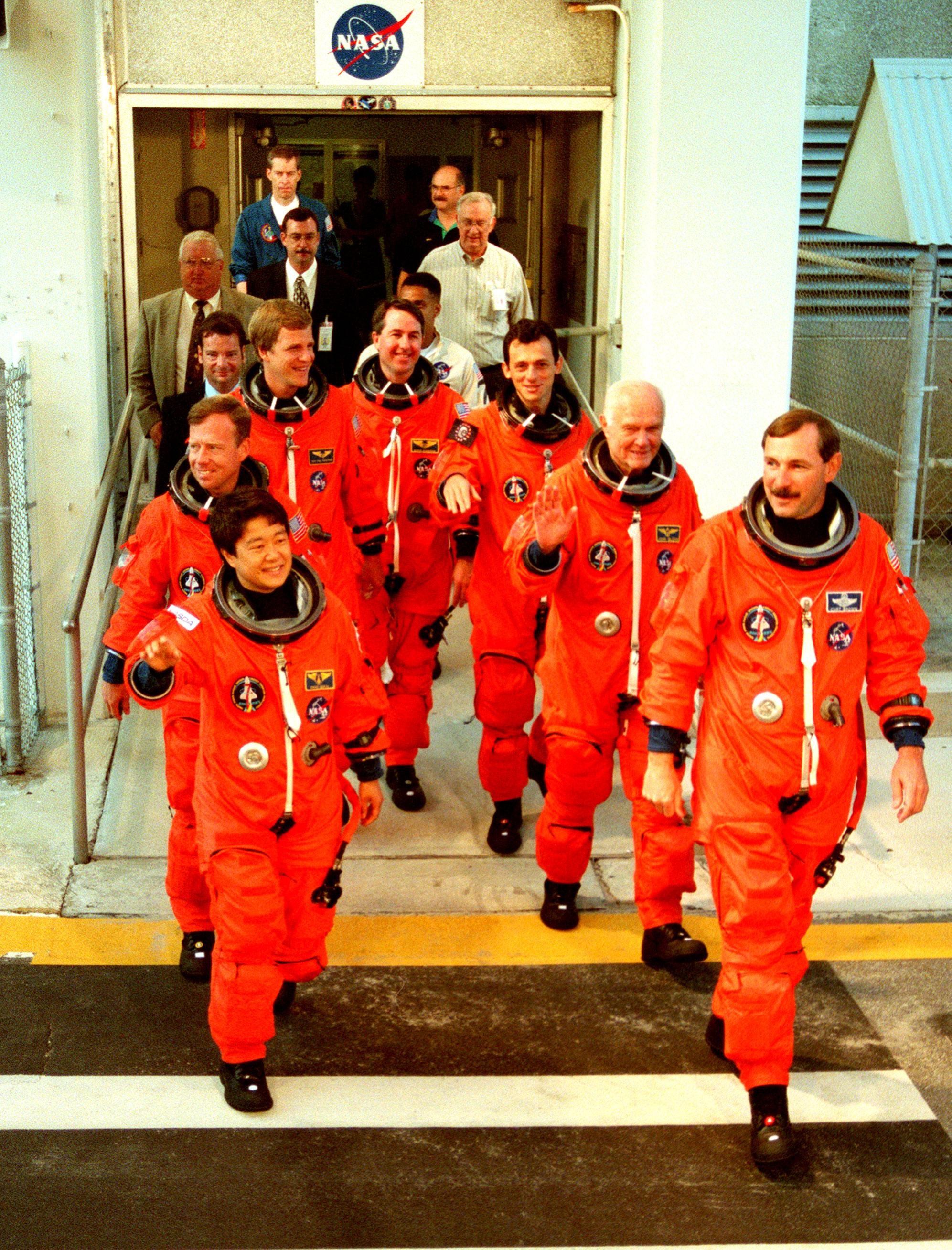 STS-95 crew members exit the Operations and Checkout Building where they suited up before leaving for Launch Pad 39-B. Pictured are (clockwise from lower left) Payload Specialist Chiaki Mukai (M.D., Ph.D.), representing the National Space Development Agency of Japan (NASDA), Pilot Steven W. Lindsey, Mission Specialist Scott E. Parazynski, Mission Specialist Stephen K. Robinson, Mission Specialist Pedro Duque of Spain, representing the European Space Agency (ESA), Payload Specialist John H. Glenn Jr., senator from Ohio, and Mission Commander Curtis L. Brown. The STS-95 crew are at KSC to participate in a Terminal Countdown Demonstration Test (TCDT) which includes mission familiarization activities, emergency egress training, and the simulated main engine cut-off exercise. The STS-95 mission, targeted for liftoff on Oct. 29, includes research payloads such as the Spartan solar-observing deployable spacecraft, the Hubble Space Telescope Orbital Systems Test Platform, the International Extreme Ultraviolet Hitchhiker, as well as the SPACEHAB single module with experiments on space flight and the aging process. Following the TCDT, the crew will be returning to Houston for final flight preparations