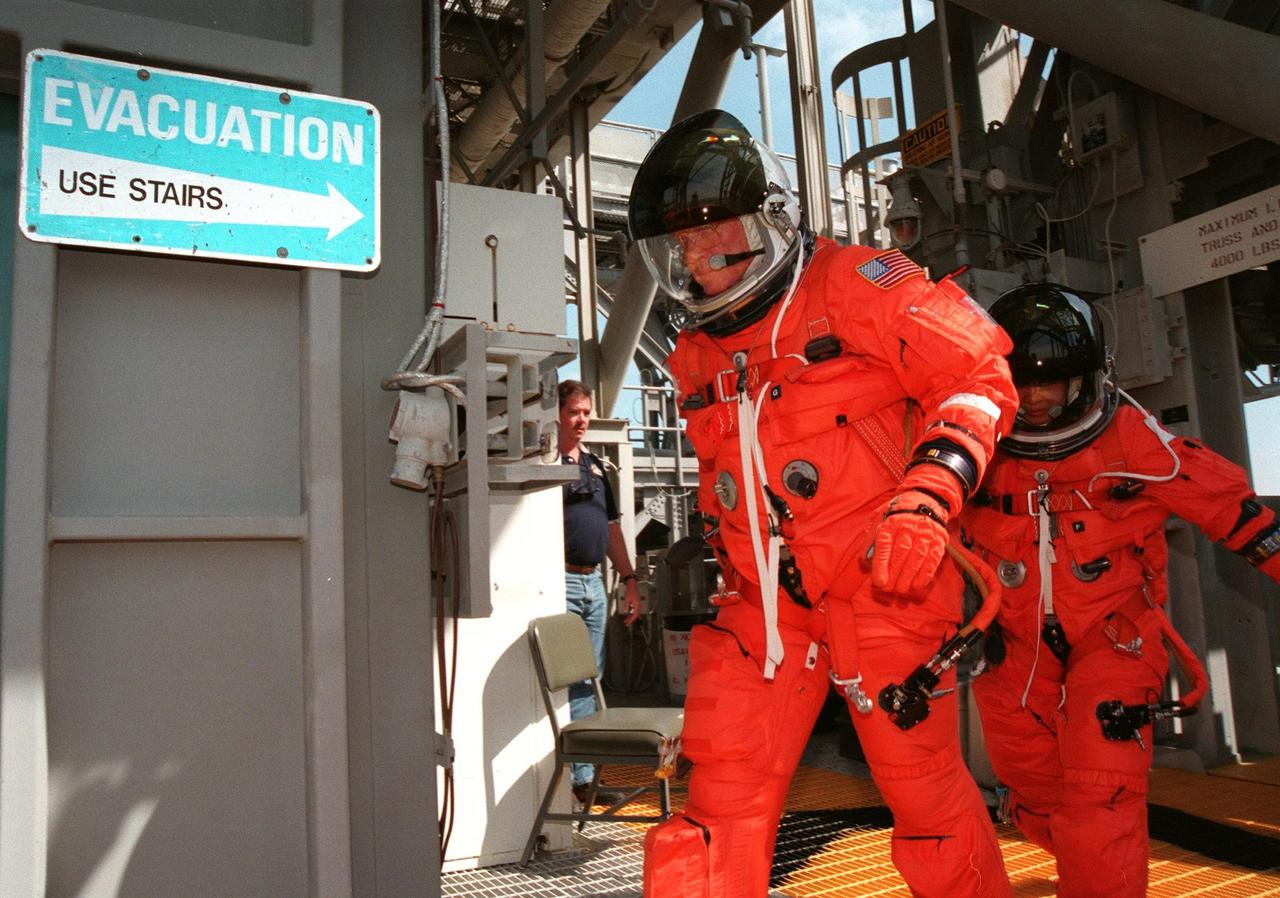 STS-95 Payload Specialists John H. Glenn Jr. (left), senator from Ohio, and Chiaki Mukai (M.D., Ph.D.) (right), representing the National Space Development Agency of Japan (NASDA), hurry toward the basket at the 195-foot level of Launch Pad 39B during an emergency egress exercise. Glenn and Mukai, along with other crew members, are at KSC to participate in the Terminal Countdown Demonstration Test (TCDT) which includes mission familiarization activities, emergency egress training, and a simulated main engine cutoff. The other crew members are Pilot Steven W. Lindsey, Mission Specialist Scott E. Parazynski, Mission Specialist Pedro Duque of Spain, representing the European Space Agency (ESA), Mission Specialist Stephen K. Robinson, and Mission Commander Curtis L. Brown. The STS-95 mission, targeted for liftoff on Oct. 29, includes research payloads such as the Spartan solar-observing deployable spacecraft, the Hubble Space Telescope Orbital Systems Test Platform, the International Extreme Ultraviolet Hitchhiker, as well as the SPACEHAB single module with experiments on space flight and the aging process. Following the TCDT, the crew will be returning to Houston for final flight preparations