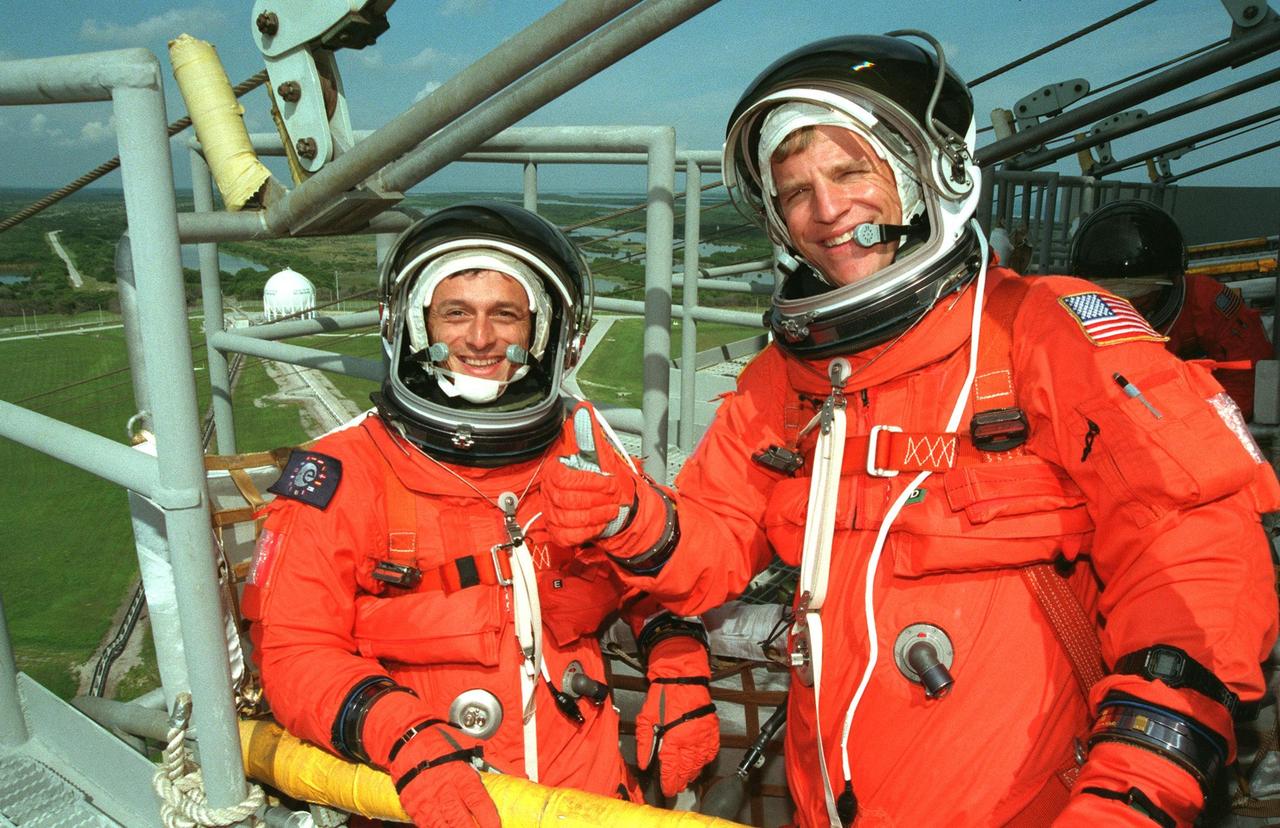 STS-95 Mission Specialist Pedro Duque of Spain (left), representing the European Space Agency (ESA), and Mission Specialist Scott E. Parazynski (right) signal they are ready to leave Launch Pad 39B in the slidewire basket during an emergency egress exercise. Duque and Parazynski, along with other crew members, are at KSC to participate in the Terminal Countdown Demonstration Test (TCDT) which includes mission familiarization activities, emergency egress training, and a simulated main engine cutoff. Not shown are Mission Commander Curtis L. Brown, Pilot Steven W. Lindsey, Mission Specialist Stephen K. Robinson, Payload Specialists John H. Glenn Jr., senator from Ohio, and Chiaki Mukai (M.D., Ph.D.), representing the National Space Development Agency of Japan (NASDA). The STS-95 mission, targeted for liftoff on Oct. 29, includes research payloads such as the Spartan solar-observing deployable spacecraft, the Hubble Space Telescope Orbital Systems Test Platform, the International Extreme Ultraviolet Hitchhiker, as well as the SPACEHAB single module with experiments on space flight and the aging process. Following the TCDT, the crew will be returning to Houston for final flight preparations
