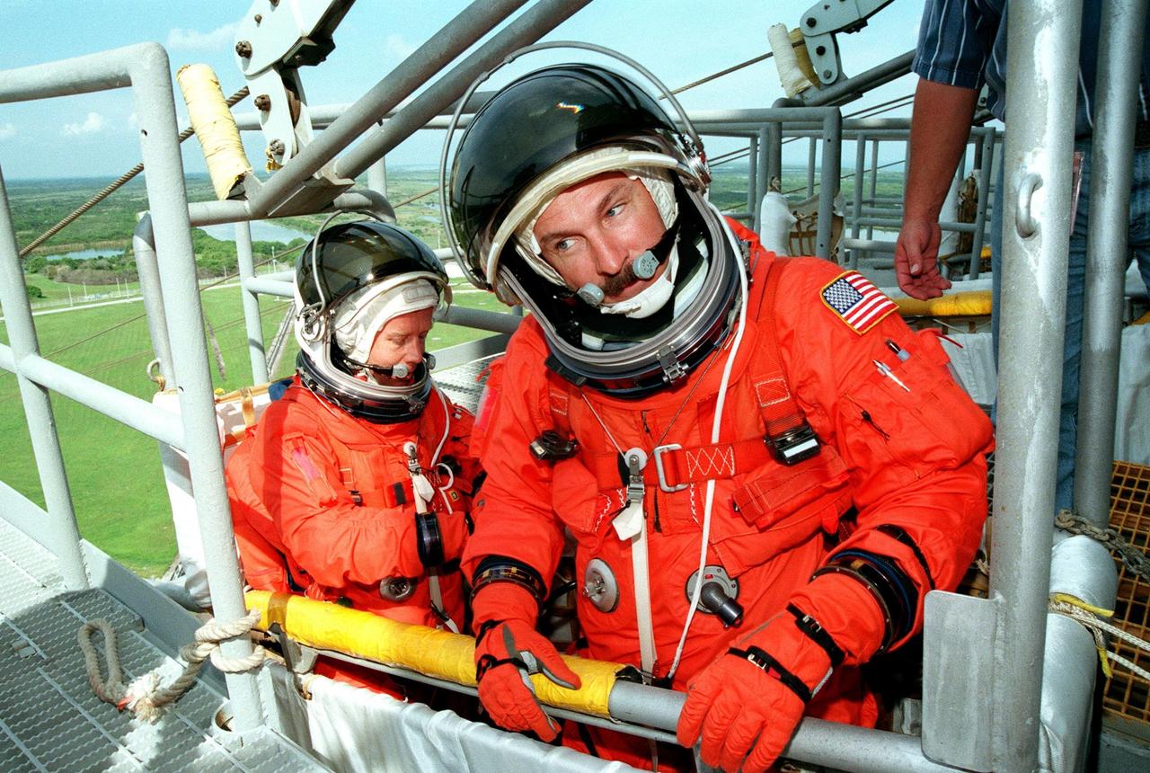STS-95 Pilot Steven W. Lindsey (left) and Mission Commander Curtis L. Brown are ready to leave Launch Pad 39B in the slidewire basket during an emergency egress exercise. Lindsey and Brown, along with other crew members, are at KSC to participate in the Terminal Countdown Demonstration Test (TCDT) which includes mission familiarization activities, emergency egress training, and a simulated main engine cutoff. Not shown are Mission Specialist Pedro Duque of Spain, representing the European Space Agency (ESA), Mission Specialist Scott E. Parazynski, Mission Specialist Stephen K. Robinson, Payload Specialists John H. Glenn Jr., senator from Ohio, and Chiaki Mukai (M.D., Ph.D.), representing the National Space Development Agency of Japan (NASDA). The STS-95 mission, targeted for liftoff on Oct. 29, includes research payloads such as the Spartan solar-observing deployable spacecraft, the Hubble Space Telescope Orbital Systems Test Platform, the International Extreme Ultraviolet Hitchhiker, as well as the SPACEHAB single module with experiments on space flight and the aging process. Following the TCDT, the crew will be returning to Houston for final flight preparations