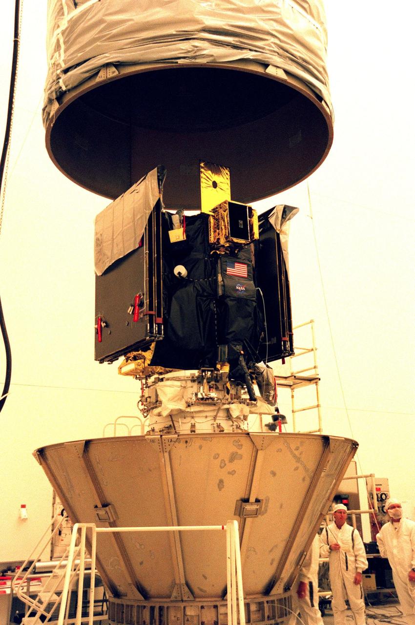 KENNEDY SPACE CENTER, FLA. -- In the Defense Satellite Communications Systems Processing Facility (DPF), Cape Canaveral Air Station (CCAS), the lower part of Deep Space 1 is enclosed with the conical section leaves of the payload transportation container prior to its move to Launch Pad 17A. The spacecraft is targeted for launch Oct. 25 aboard a Boeing Delta 7326 rocket. The first flight in NASA's New Millennium Program, Deep Space 1 is designed to validate 12 new technologies for scientific space missions of the next century, including the engine. Propelled by the gas xenon, the engine is being flight-tested for future deep space and Earth-orbiting missions. Deceptively powerful, the ion drive emits only an eerie blue glow as ionized atoms of xenon are pushed out of the engine. While slow to pick up speed, over the long haul it can deliver 10 times as much thrust per pound of fuel as liquid or solid fuel rockets. Other onboard experiments include software that tracks celestial bodies so the spacecraft can make its own navigation decisions without the intervention of ground controllers. Deep Space 1 will complete most of its mission objectives within the first two months, but will also do a flyby of a near-Earth asteroid, 1992 KD, in July 1999