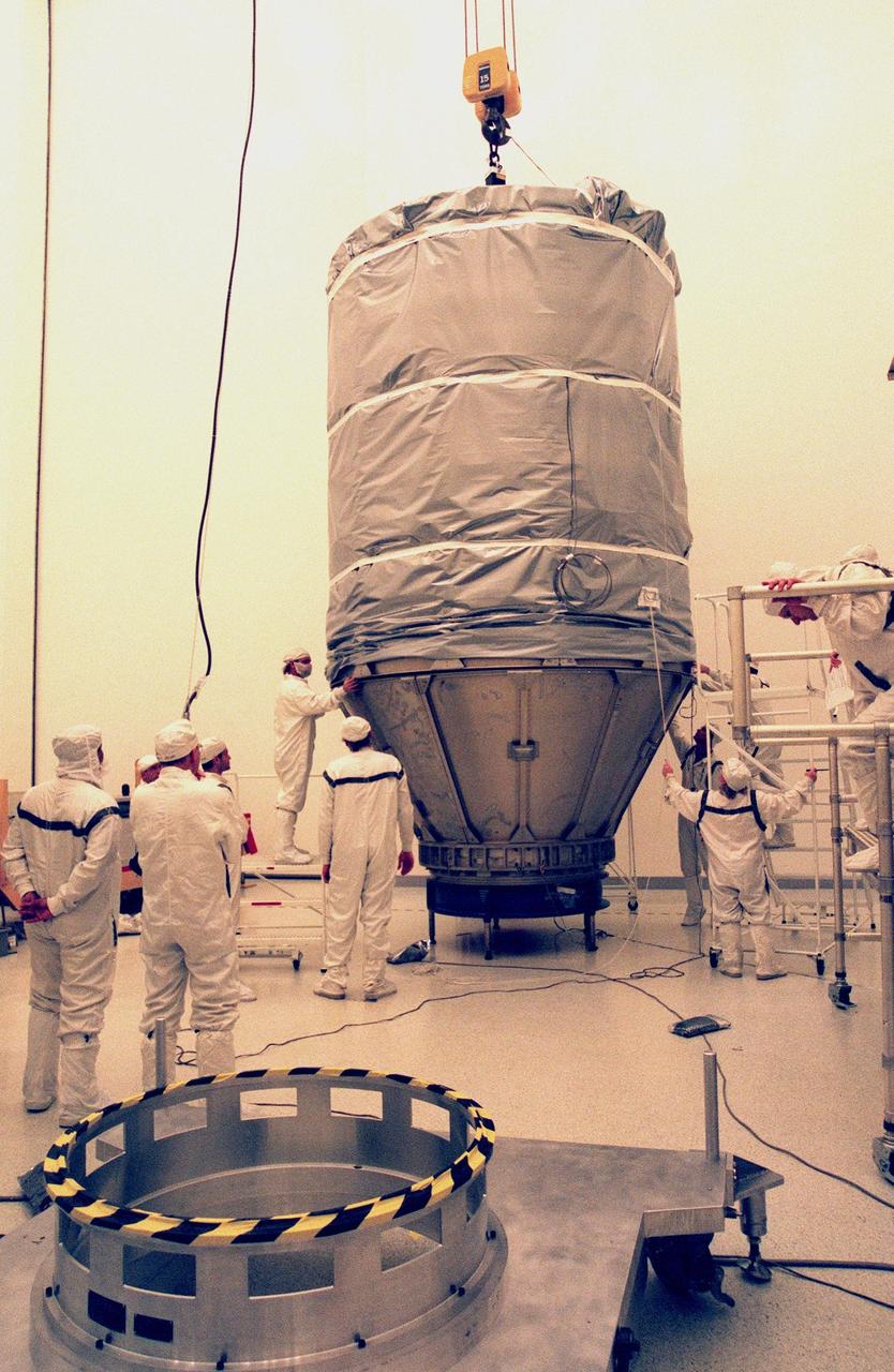 KENNEDY SPACE CENTER, FLA. -- In the Defense Satellite Communications Systems Processing Facility (DPF), Cape Canaveral Air Station (CCAS), after covering the lower portion of Deep Space 1, workers adjust the anti-static blanket covering the upper portion. The blanket will protect the spacecraft during transport to the launch pad. Deep Space 1 is the first flight in NASA's New Millennium Program, and is designed to validate 12 new technologies for scientific space missions of the next century, including the engine. Propelled by the gas xenon, the engine is being flight-tested for future deep space and Earth-orbiting missions. Deceptively powerful, the ion drive emits only an eerie blue glow as ionized atoms of xenon are pushed out of the engine. While slow to pick up speed, over the long haul it can deliver 10 times as much thrust per pound of fuel as liquid or solid fuel rockets. Other onboard experiments include software that tracks celestial bodies so the spacecraft can make its own navigation decisions without the intervention of ground controllers. Deep Space 1 will complete most of its mission objectives within the first two months, but will also do a flyby of a near-Earth asteroid, 1992 KD, in July 1999. Deep Space 1 will be launched aboard a Boeing Delta 7326 rocket from Launch Pad 17A, CCAS