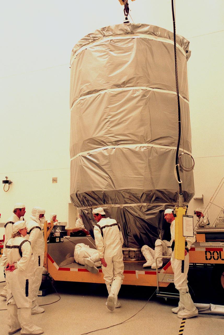 KENNEDY SPACE CENTER, FLA. - Wrapped in an antistatic blanket for protection, Deep Space 1 is moved out of the Defense Satellite Communications System Processing Facility (DPF) at Cape Canaveral Air Station (CCAS) for its trip to Launch Pad 17A. The spacecraft will be launched aboard Boeing's Delta 7326 rocket in October. The first flight in NASA's New Millennium Program, Deep Space 1 is designed to validate 12 new technologies for scientific space missions of the next century, including an ion propulsion engine. Propelled by the gas xenon, the engine is being flight tested for future deep space and Earth-orbiting missions. Deceptively powerful, the ion drive emits only an eerie blue glow as ionized atoms of xenon are pushed out of the engine. While slow to pick up speed, over the long haul it can deliver 10 times as much thrust per pound of fuel as liquid or solid fuel rockets. Other onboard experiments include softwre that tracks celestial bodies so the spacecraft can make its own navigation decisions without the intervention of ground controllers. Deep Space 1 will complete most of its mission objectives within the firs two months, but will also make a flyby of a near-Earth asteroid, 1992 KD, in July 1999.