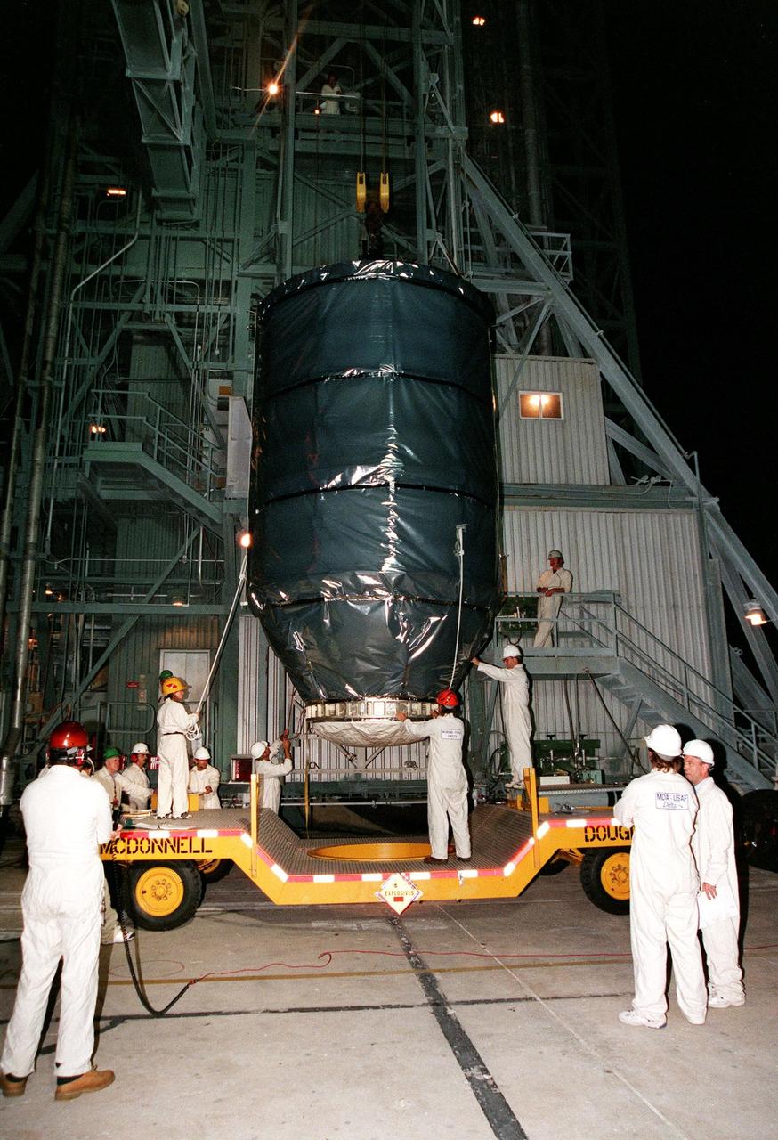 KENNEDY SPACE CENTER, FLA. -- Wrapped in an anti-static blanket for protection, Deep Space 1 is lifted out of the transporter that carried it to Launch Pad 17A at Cape Canaveral Air Station. The spacecraft will be launched aboard a Boeing Delta 7326 rocket on Oct. 25. Deep Space 1 is the first flight in NASA's New Millennium Program, and is designed to validate 12 new technologies for scientific space missions of the next century, including the engine. Propelled by the gas xenon, the engine is being flight-tested for future deep space and Earth-orbiting missions. Deceptively powerful, the ion drive emits only an eerie blue glow as ionized atoms of xenon are pushed out of the engine. While slow to pick up speed, over the long haul it can deliver 10 times as much thrust per pound of fuel as liquid or solid fuel rockets. Other onboard experiments include software that tracks celestial bodies so the spacecraft can make its own navigation decisions without the intervention of ground controllers. Deep Space 1 will complete most of its mission objectives within the first two months, but will also do a flyby of a near-Earth asteroid, 1992 KD, in July 1999