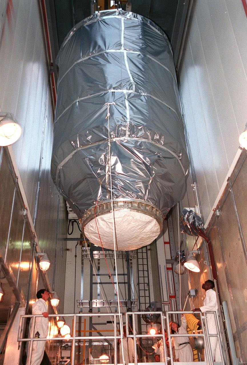 KENNEDY SPACE CENTER, FLA. -- On Launch Pad 17A at Cape Canaveral Air Station, Deep Space 1 is lowered in the white room for installation on a Boeing Delta 7326 rocket . The spacecraft is targeted for launch on Oct. 25. Deep Space 1 is the first flight in NASA's New Millennium Program, and is designed to validate 12 new technologies for scientific space missions of the next century, including the engine. Propelled by the gas xenon, the engine is being flight-tested for future deep space and Earth-orbiting missions. Deceptively powerful, the ion drive emits only an eerie blue glow as ionized atoms of xenon are pushed out of the engine. While slow to pick up speed, over the long haul it can deliver 10 times as much thrust per pound of fuel as liquid or solid fuel rockets. Other onboard experiments include software that tracks celestial bodies so the spacecraft can make its own navigation decisions without the intervention of ground controllers. Deep Space 1 will complete most of its mission objectives within the first two months, but will also do a flyby of a near-Earth asteroid, 1992 KD, in July 1999