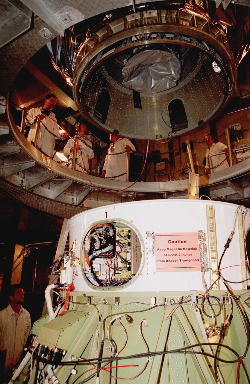 KENNEDY SPACE CENTER, FLA. -- On Launch Pad 17A at Cape Canaveral Air Station, Deep Space 1 is lowered toward the second stage of a Boeing Delta 7326 rocket. The adapter on the spacecraft can be seen surrounding the booster motor. Targeted for launch on Oct. 25, Deep Space 1 is the first flight in NASA's New Millennium Program, and is designed to validate 12 new technologies for scientific space missions of the next century, including the engine. Propelled by the gas xenon, the engine is being flight-tested for future deep space and Earth-orbiting missions. Deceptively powerful, the ion drive emits only an eerie blue glow as ionized atoms of xenon are pushed out of the engine. While slow to pick up speed, over the long haul it can deliver 10 times as much thrust per pound of fuel as liquid or solid fuel rockets. Other onboard experiments include software that tracks celestial bodies so the spacecraft can make its own navigation decisions without the intervention of ground controllers. Deep Space 1 will complete most of its mission objectives within the first two months, but will also do a flyby of a near-Earth asteroid, 1992 KD, in July 1999