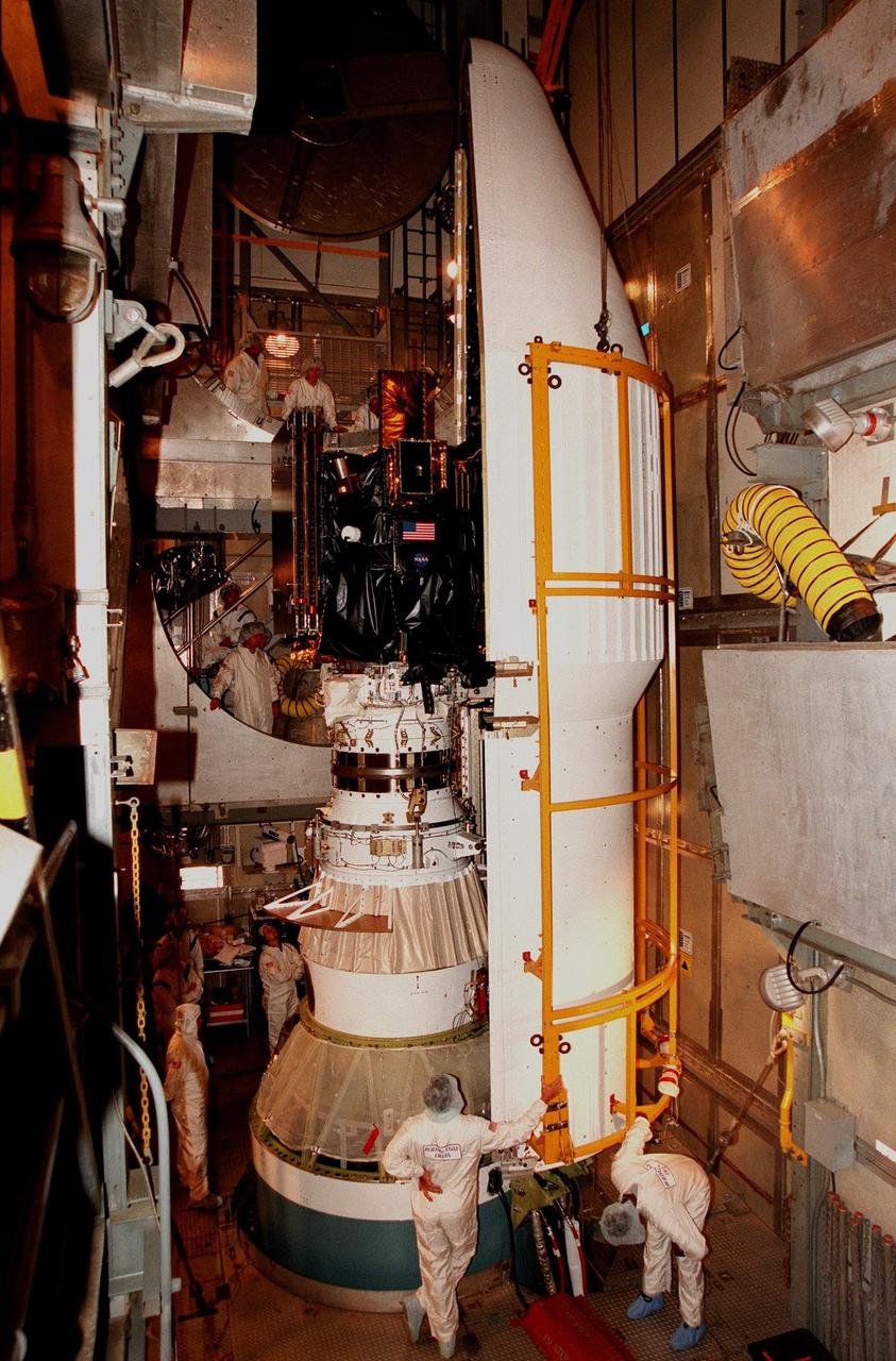 KENNEDY SPACE CENTER, FLA. -- On Launch Pad 17A at Cape Canaveral Air Station, workers begin encapsulating Deep Space 1 with the fairing (right side). Targeted for launch aboard a Boeing Delta 7326 rocket on Oct. 25, Deep Space 1 is the first flight in NASA's New Millennium Program, and is designed to validate 12 new technologies for scientific space missions of the next century, including the engine. Propelled by the gas xenon, the engine is being flight-tested for future deep space and Earth-orbiting missions. Deceptively powerful, the ion drive emits only an eerie blue glow as ionized atoms of xenon are pushed out of the engine. While slow to pick up speed, over the long haul it can deliver 10 times as much thrust per pound of fuel as liquid or solid fuel rockets. Other onboard experiments include software that tracks celestial bodies so the spacecraft can make its own navigation decisions without the intervention of ground controllers. Deep Space 1 will complete most of its mission objectives within the first two months, but will also do a flyby of a near-Earth asteroid, 1992 KD, in July 1999