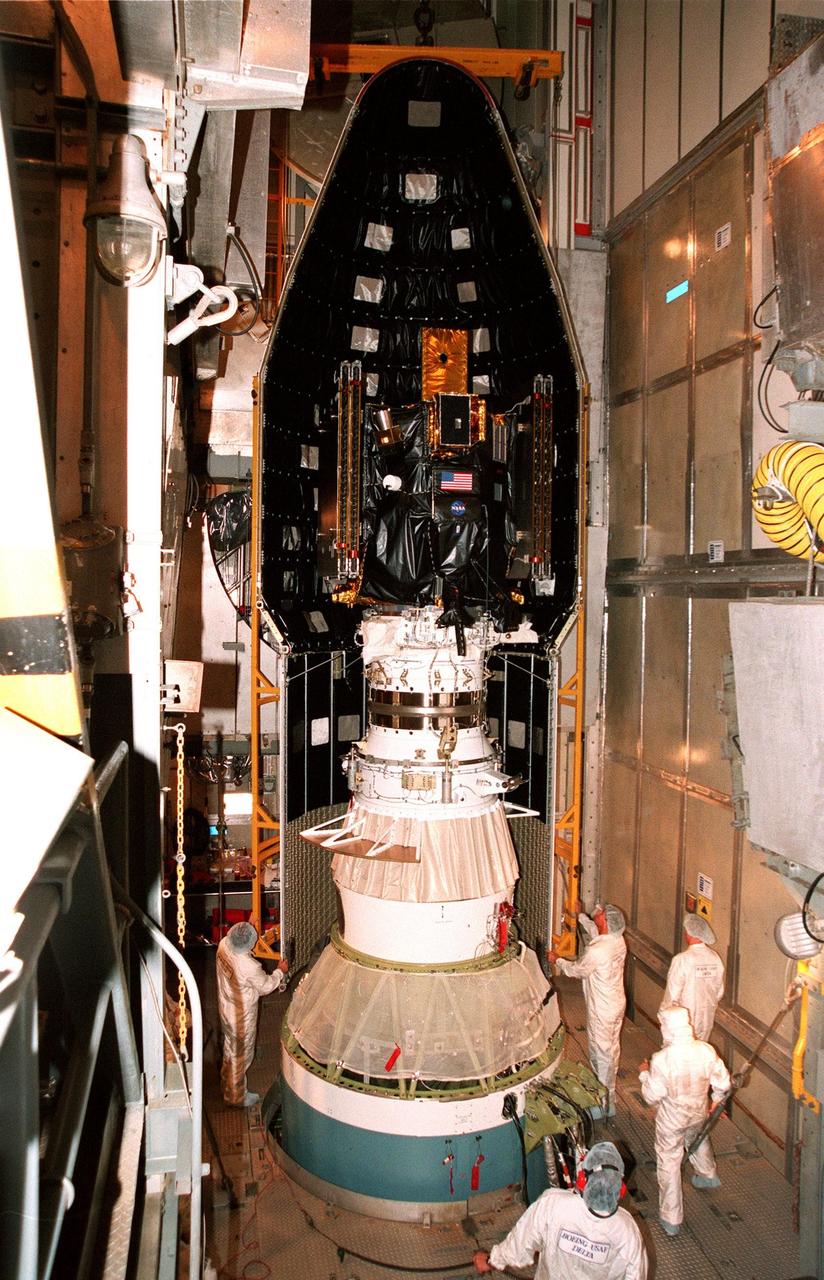 KENNEDY SPACE CENTER, FLA. -- On Launch Pad 17A at Cape Canaveral Air Station, workers maneuver part of the fairing (viewed from the inside) to encapsulate Deep Space 1. Targeted for launch aboard a Boeing Delta 7326 rocket on Oct. 25, Deep Space 1 is the first flight in NASA's New Millennium Program, and is designed to validate 12 new technologies for scientific space missions of the next century, including the engine. Propelled by the gas xenon, the engine is being flight-tested for future deep space and Earth-orbiting missions. Deceptively powerful, the ion drive emits only an eerie blue glow as ionized atoms of xenon are pushed out of the engine. While slow to pick up speed, over the long haul it can deliver 10 times as much thrust per pound of fuel as liquid or solid fuel rockets. Other onboard experiments include software that tracks celestial bodies so the spacecraft can make its own navigation decisions without the intervention of ground controllers. Deep Space 1 will complete most of its mission objectives within the first two months, but will also do a flyby of a near-Earth asteroid, 1992 KD, in July 1999