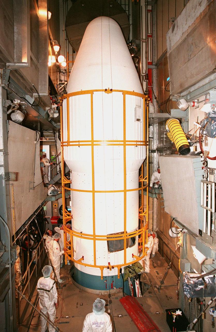 KENNEDY SPACE CENTER, FLA. -- On Launch Pad 17A at Cape Canaveral Air Station, workers check make a final check of the fairing encapsulating Deep Space 1, which is targeted for launch aboard a Boeing Delta II rocket on Oct. 24. The first flight in NASA's New Millennium Program, Deep Space 1 is designed to validate 12 new technologies for scientific space missions of the next century, including the engine. Propelled by the gas xenon, the engine is being flight-tested for future deep space and Earth-orbiting missions. Deceptively powerful, the ion drive emits only an eerie blue glow as ionized atoms of xenon are pushed out of the engine. While slow to pick up speed, over the long haul it can deliver 10 times as much thrust per pound of fuel as liquid or solid fuel rockets. Other onboard experiments include software that tracks celestial bodies so the spacecraft can make its own navigation decisions without the intervention of ground controllers. Deep Space 1 will complete most of its mission objectives within the first two months, but will also do a flyby of a near-Earth asteroid, 1992 KD, in July 1999