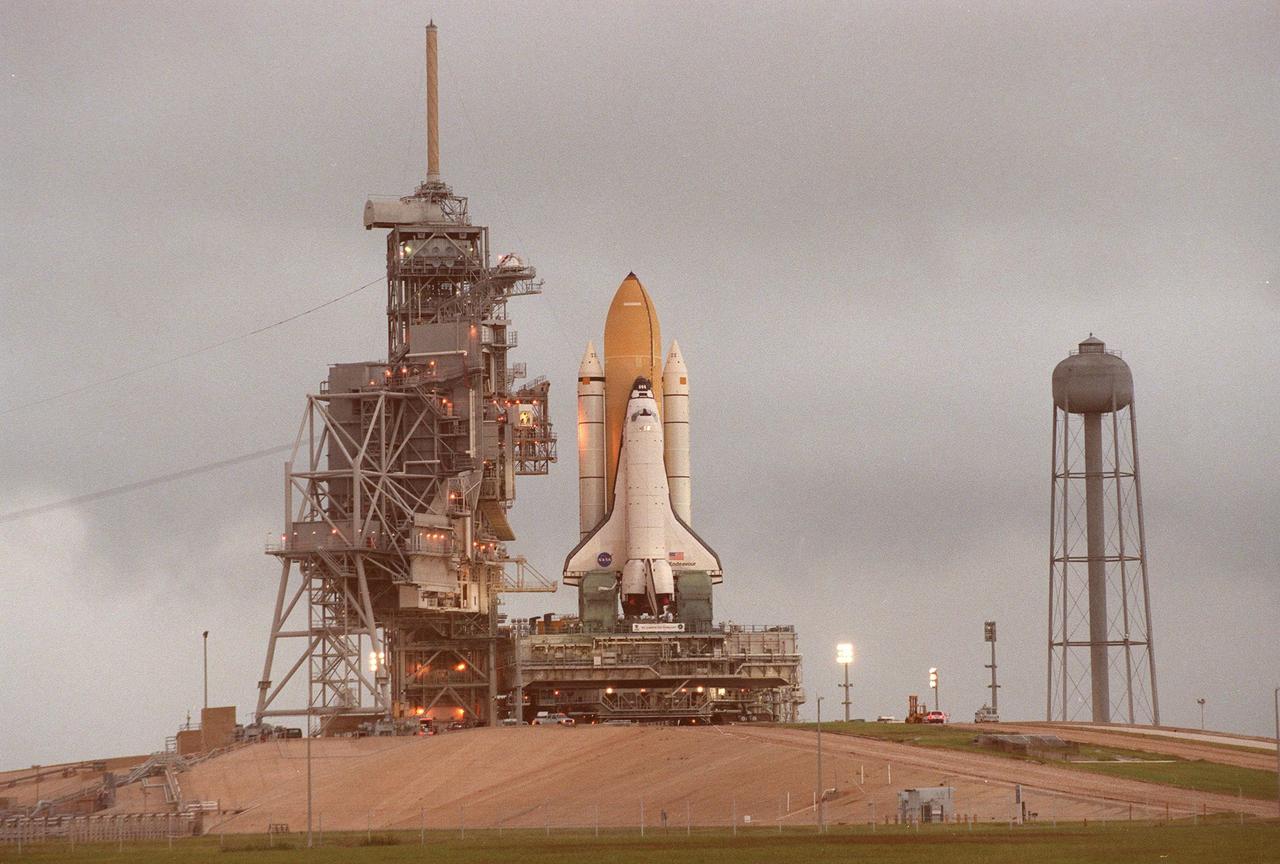 KENNEDY SPACE CENTER,  Fla. -- Towering atop the mobile launcher platform and crawler transporter in the early morning light, Space Shuttle Endeavour arrives at Launch Pad 39A after rollout from the Vehicle Assembly Building. At its left are the Rotating Service Structure and the Fixed Service Structure; at the right is the 300,000-gallon water tank, part of the sound suppression water system. While at the pad, the orbiter, external tank and solid rocket boosters will undergo final preparations for the STS-88 launch targeted for Dec. 3, 1998. Mission STS-88 is the first U.S. flight for the assembly of the International Space Station and will carry the Unity connecting module. While on orbit, the flight crew will deploy Unity from the payload bay and connect it to the Russian-built Zarya control module which will be in orbit at that time. Unity will be the main connecting point for later U.S. station modules and components. More than 40 launches are planned over five years involving the resources and expertise of 16 cooperating nations. Comprising the STS-88 crew are Commander Robert D. Cabana, Pilot Frederick W. "Rick" Sturckow, Mission Specialists Nancy J. Currie, Jerry L. Ross, James H. Newman and Russian cosmonaut Sergei Konstantinovich Krikalev. Ross and Newman will make three spacewalks to connect power, data and utility lines and install exterior equipment