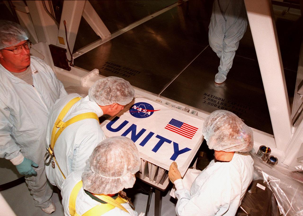 Examining the nameplate for the Unity connecting module, in the Space Station Processing Facility, are (left to right) Joe Schweiger and Tommy Annis, of Boeing-KSC, and Nancy Tolliver, of Boeing-Huntsville. An unidentified worker behind them looks on. Part of the International Space Station, Unity was expected to be transported to Launch Pad 39A on Oct. 26 for launch aboard Space Shuttle Endeavour on Mission STS-88 in December. The Unity is a connecting passageway to the living and working areas of ISS. While on orbit, the flight crew will deploy Unity from the payload bay and attach Unity to the Russian-built Zarya control module which will be in orbit at that time