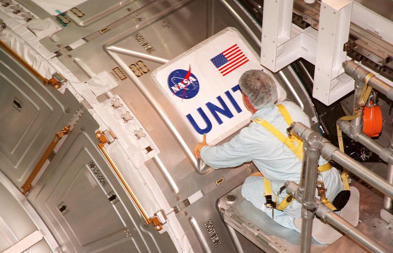 In the Space Station Processing Facility, a worker checks placement of the nameplate for the Unity connecting module, part of the International Space Station. Unity was expected to be transported to Launch Pad 39A on Oct. 26 for launch aboard Space Shuttle Endeavour on Mission STS-88 in December. The Unity is a connecting passageway to the living and working areas of ISS. While on orbit, the flight crew will deploy Unity from the payload bay and attach Unity to the Russian-built Zarya control module which will be in orbit at that time