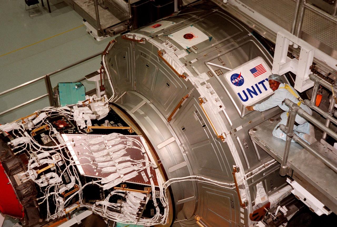 In the Space Station Processing Facility, Joan Higgenbotham, with KSC's Astronaut Office Computer Support, checks placement of the nameplate for the Unity connecting module, part of the International Space Station. Unity was expected to be transported to Launch Pad 39A on Oct. 26 for launch aboard Space Shuttle Endeavour on Mission STS-88 in December. The Unity is a connecting passageway to the living and working areas of ISS. While on orbit, the flight crew will deploy Unity from the payload bay and attach Unity to the Russian-built Zarya control module which will be in orbit at that time