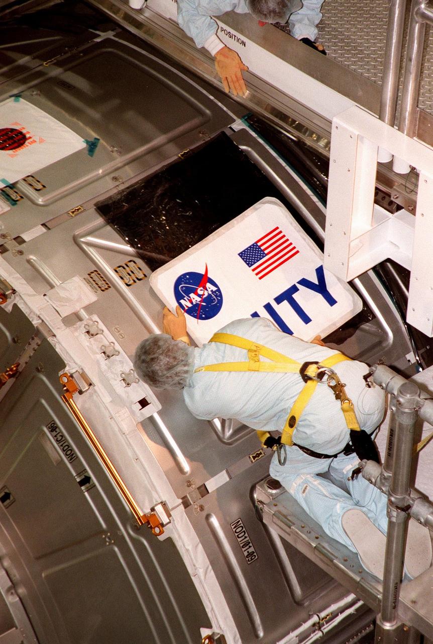 In the Space Station Processing Facility, a worker checks placement of the nameplate to be attached to the Unity connecting module, part of the International Space Station. Unity was expected to be transported to Launch Pad 39A on Oct. 26 for launch aboard Space Shuttle Endeavour on Mission STS-88 in December. The Unity is a connecting passageway to the living and working areas of ISS. While on orbit, the flight crew will deploy Unity from the payload bay and attach Unity to the Russian-built Zarya control module which will be in orbit at that time