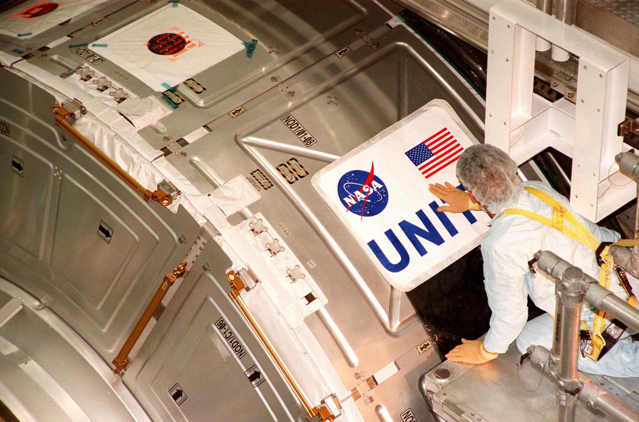 In the Space Station Processing Facility, a worker places the nameplate on the side of the Unity connecting module, part of the International Space Station. Unity was expected to be transported to Launch Pad 39A on Oct. 26 for launch aboard Space Shuttle Endeavour on Mission STS-88 in December. The Unity is a connecting passageway to the living and working areas of ISS. While on orbit, the flight crew will deploy Unity from the payload bay and attach Unity to the Russian-built Zarya control module which will be in orbit at that time