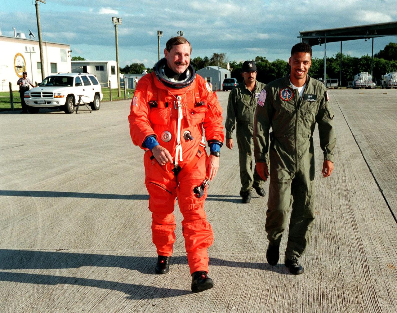 STS-95 Mission Commander Curtis L. Brown Jr. (left) leaves the Shuttle Landing Facility (SLF) enroute to the Shuttle Training Aircraft (STA). He is accompanied by two suit technicians, Ray Cuevas (middle) and Carlous Gillis (right). Brown will be practicing Shuttle landing and takeoffs at the SLF prior to launch. The STA is designed to fly like the Shuttle. STS-95 is expected to launch at 2 p.m. EST on Oct. 29, last 8 days, 21 hours and 49 minutes, and land at 11:49 a.m. EST on Nov. 7