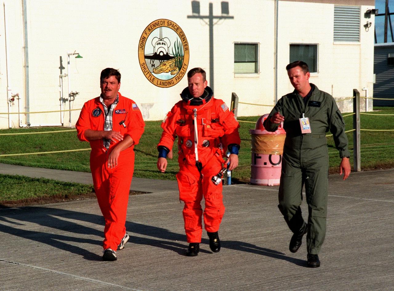 STS-95 Pilot Steven K. Lindsey leaves the Shuttle Landing Facility (SLF) enroute to the Shuttle Training Aircraft (STA). He is accompanied by two suit technicians, Mike Birkenseher (left) and Paul Reylea (right). Lindsey will be practicing Shuttle landing and takeoffs at the SLF on the STA, which is designed to fly like the Shuttle, prior to launch. STS-95 is expected to launch at 2 p.m. EST on Oct. 29, last 8 days, 21 hours and 49 minutes, and land at 11:49 a.m. EST on Nov. 7