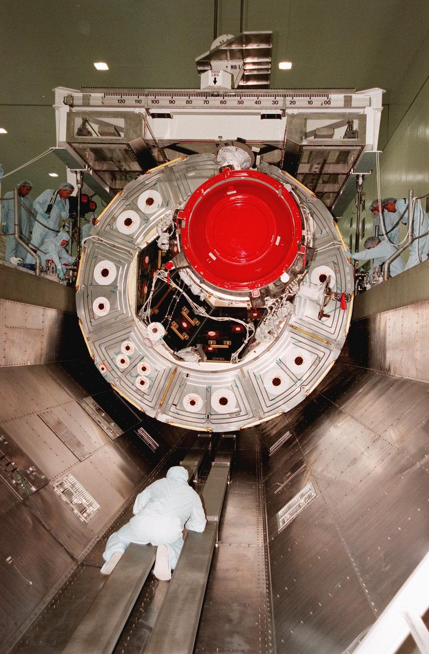 In the Space Station Processing Facility, workers at the side and on the floor of the payload canister guide the Unity connecting module into position for transfer to the launch pad. Part of the International Space Station (ISS), Unity is scheduled for launch aboard Space Shuttle Endeavour on Mission STS-88 in December. The Unity is a connecting passageway to the living and working areas of ISS. While on orbit, the flight crew will deploy Unity from the payload bay and attach Unity to the Russian-built Zarya control module which will be in orbit at that time