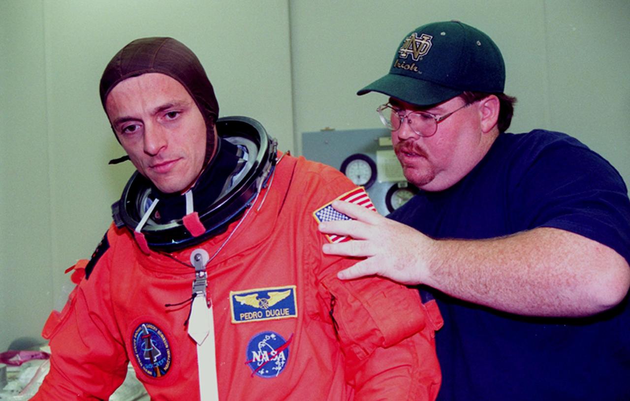 In the Operations and Checkout Building, STS-95 Mission Specialist Pedro Duque of Spain, with the European Space Agency, gets help with his suit from suit technician Tommy McDonald. The STS-95 crew were conducting flight crew equipment fit checks prior to launch on Oct. 29. STS-95 is expected to launch at 2 p.m. EST on Oct. 29, last 8 days, 21 hours and 49 minutes, and land at 11:49 a.m. EST on Nov. 7