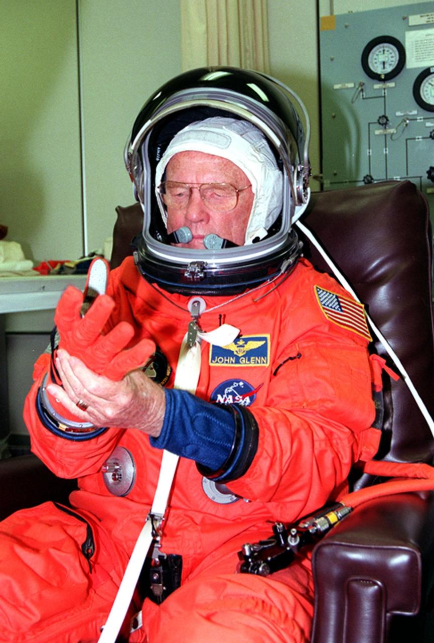 In the Operations and Checkout Building, STS-95 Payload Specialist John H. Glenn Jr. pulls on a glove, part of his equipment check. The STS-95 crew were conducting flight crew equipment fit checks prior to launch on Oct. 29. STS-95 is expected to launch at 2 p.m. EST on Oct. 29, last 8 days, 21 hours and 49 minutes, and land at 11:49 a.m. EST on Nov. 7