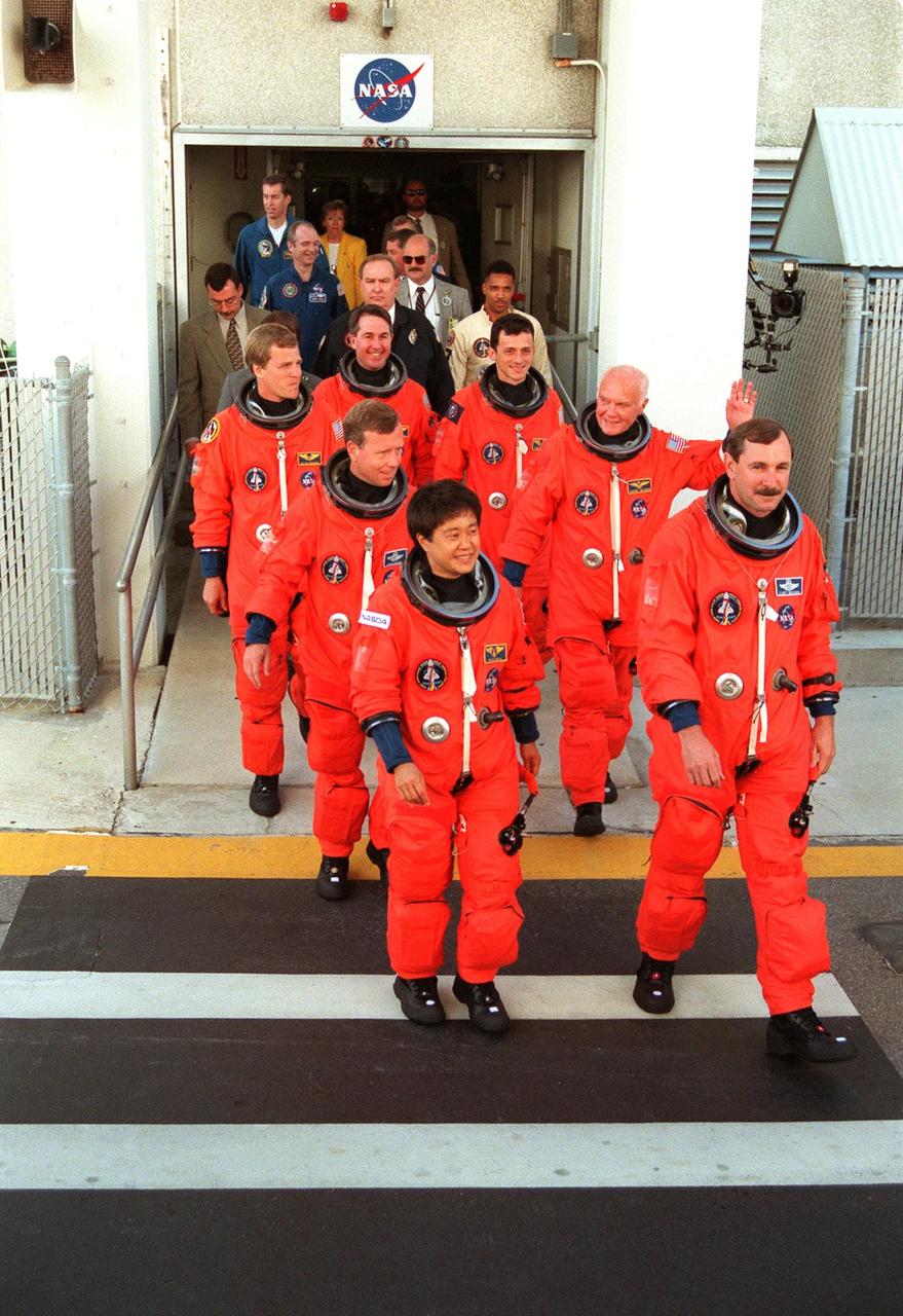The STS-95 crew leave the Operations and Checkout Building in their flight suits for their trip to Launch Pad 39B. Leading the group to the Astrovan for the ride to Launch Pad 39B is Mission Commander Curtis L. Brown Jr. (far right) next to Payload Specialist Chiaki Mukai (left), with the National Space Development Agency of Japan (NASDA). Behind them are (2nd row) Pilot Steven W. Lindsey (left) and Payload Specialist John H. Glenn Jr. (right), senator from Ohio; (3rd row) Mission Specialists Scott E. Parazynski (left) and Pedro Duque of Spain (right), with the European Space Agency; and Mission Specialist Stephen K. Robinson at the rear. Targeted for launch at 2 p.m. EST on Oct. 29, the mission is expected to last 8 days, 21 hours and 49 minutes, and return to KSC at 11:49 a.m. EST on Nov. 7. The STS-95 mission includes research payloads such as the Spartan solar-observing deployable spacecraft, the Hubble Space Telescope Orbital Systems Test Platform, the International Extreme Ultraviolet Hitchhiker, as well as the SPACEHAB single module with experiments on space flight and the aging process