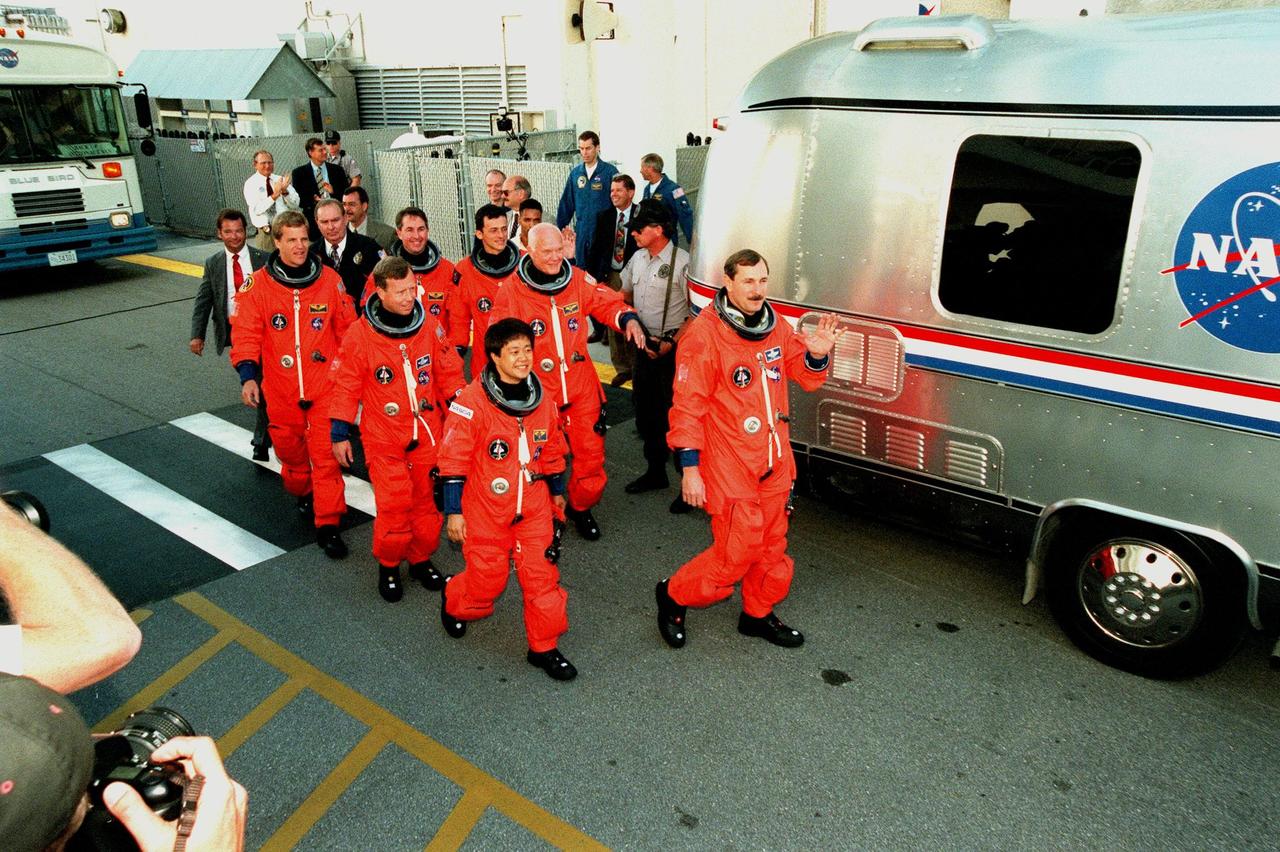 After leaving the Operations and Checkout Building, the STS-95 crew approach the Astrovan for their trip to Launch Pad 39B. Leading the group is Mission Commander Curtis L. Brown Jr. (far right), waving to the media and well-wishers; next him is Payload Specialist Chiaki Mukai (left), with the National Space Development Agency of Japan (NASDA). Behind them are (2nd row) Pilot Steven W. Lindsey (left) and Payload Specialist John H. Glenn Jr. (right), senator from Ohio; (3rd row) Mission Specialists Scott E. Parazynski , Stephen K. Robinson and Pedro Duque of Spain (right), with the European Space Agency. Targeted for launch at 2 p.m. EST on Oct. 29, the mission is expected to last 8 days, 21 hours and 49 minutes, and return to KSC at 11:49 a.m. EST on Nov. 7. The STS-95 mission includes research payloads such as the Spartan solar-observing deployable spacecraft, the Hubble Space Telescope Orbital Systems Test Platform, the International Extreme Ultraviolet Hitchhiker, as well as the SPACEHAB single module with experiments on space flight and the aging process