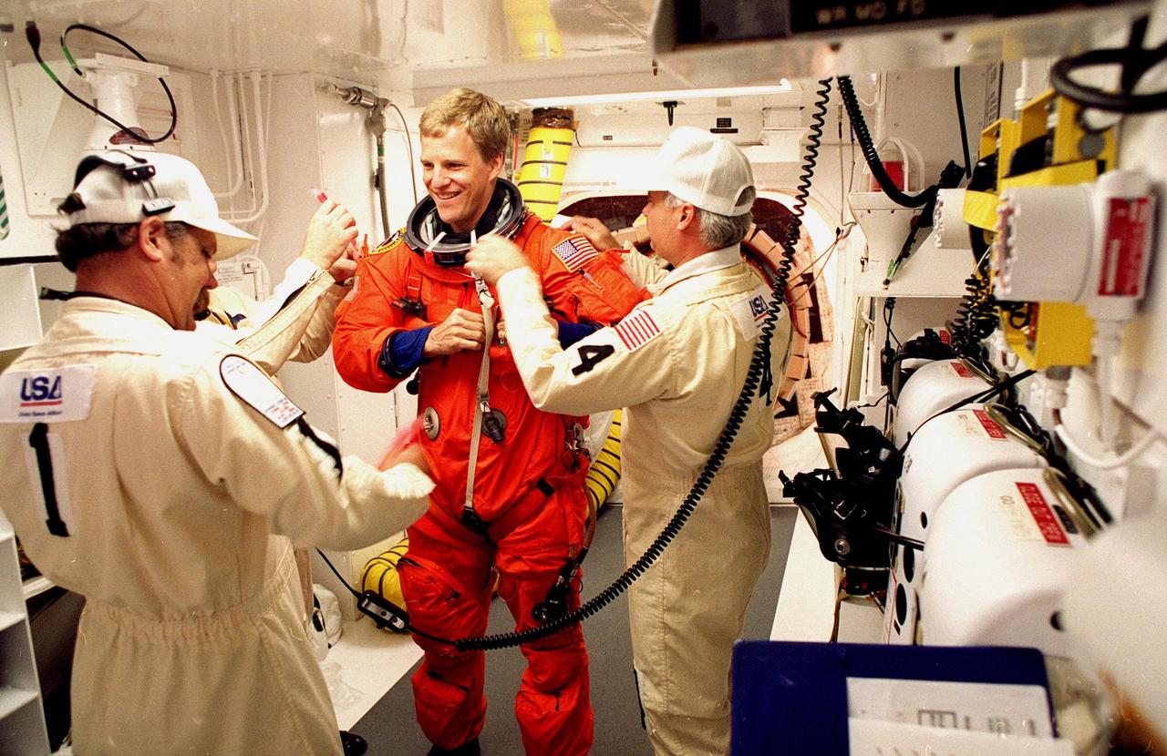 In the environmental chamber known as the white room, STS-95 Mission Specialist Scott E. Parazynski is prepared by closeout room crew members Travis Thompson (left), Danny Wyatt (partially hidden) and Chris Meinert (right) for entry into the Space Shuttle Discovery for his third flight into space. The STS-95 mission, targeted for launch at 2 p.m. EST on Oct. 29, is expected to last 8 days, 21 hours and 49 minutes, and return to KSC at 11:49 a.m. EST on Nov. 7