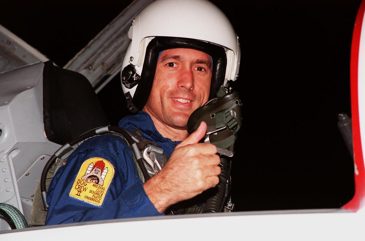 STS-88 Mission Specialist James H. Newman gives a thumbs up on his nighttime arrival at the Shuttle Landing Facility in a T-38 jet aircraft to take part in Terminal Countdown Demonstration Test (TCDT) activities. The TCDT provides the crew with simulated countdown exercises, emergency egress training, and opportunities to inspect their mission payloads in the orbiter's payload bay. Mission STS-88 is targeted for launch on Dec. 3, 1998. It is the first U.S. flight for the assembly of the International Space Station and will carry the Unity connecting module. Others in the STS-88 crew are Mission Commander Robert D. Cabana, Pilot Frederick W. "Rick" Sturckow, Mission Specialists Nancy J. Currie, Jerry L. Ross, and Sergei Krikalev, a Russian cosmonaut. Ross and Newman will make three spacewalks to connect power, data and utility lines and install exterior equipment