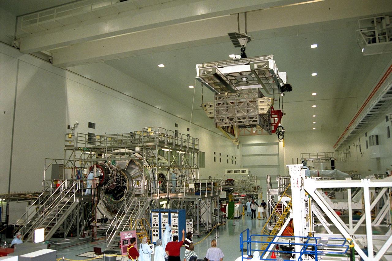 The Photovoltaic Module 1 Integrated Equipment Assembly (IEA) is moved past Node 1, seen at left, of the International Space Station (ISS) in Kennedy Space Center’s Space Station Processing Facility (SSPF). The IEA will be processed at the SSPF for flight on STS-97, scheduled for launch in April 1999. The IEA is one of four integral units designed to generate, distribute, and store power for the ISS. It will carry solar arrays, power storage batteries, power control units, and a thermal control system. The 16-foot-long, 16,850-pound unit is now undergoing preflight preparations in the SSPF