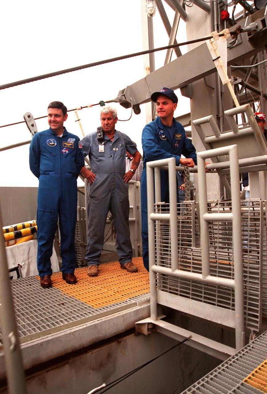 KENNEDY SPACE CENTER,  Fla. -- STS-88 Mission Commander Robert D. Cabana (left) and Pilot Frederick W. "Rick" Sturckow (right) examine part of the emergency egress system at Launch Pad 39A, during Terminal Countdown Demonstration Test (TCDT) activities. Standing between them is an unidentified KSC worker. The crew are at KSC to participate in the Terminal Countdown Demonstration Test (TCDT), a dress rehearsal for launch. Mission STS-88 is targeted for launch on Dec. 3, 1998. It is the first U.S. flight for the assembly of the International Space Station and will carry the Unity connecting module. Unity will be mated with the already orbiting Russian-built Zarya control module. The 12-day mission includes three planned spacewalks to connect power, data and utility lines and install exterior equipment