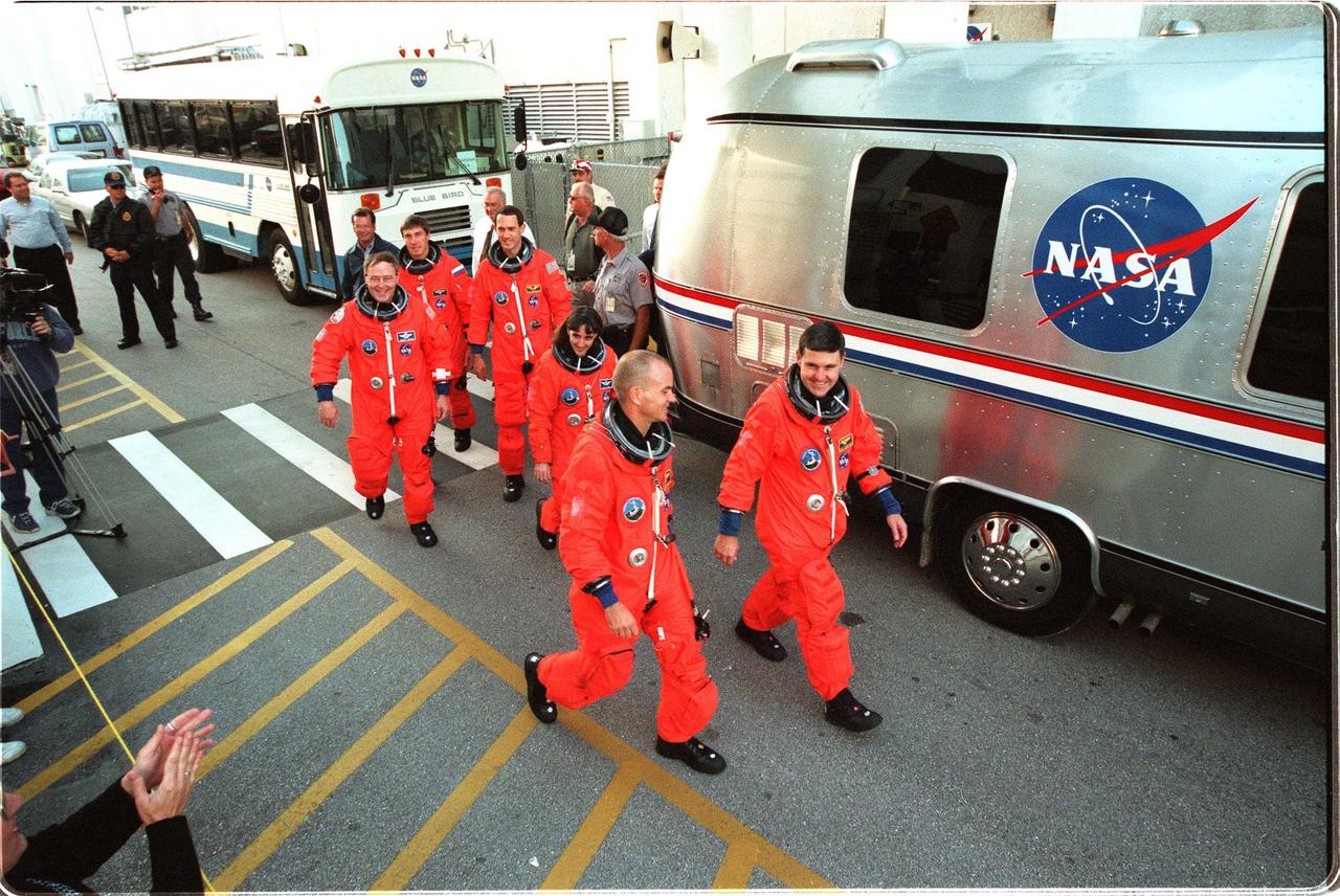 After suiting up for their practice countdown exercise, STS-88 crew members head for the bus outside the Operations and Checkout Building for the trip to Launch Pad 39A. From left they are Mission Specialist Jerry L. Ross, Mission Specialist Sergei Krikalev, who is a Russian cosmonaut, Mission Specialists James H. Newman and Nancy J. Currie, Pilot Frederick W. "Rick" Sturckow, and Mission Commander Robert D. Cabana. The crew are at KSC to participate in the Terminal Countdown Demonstration Test (TCDT) which includes mission familiarization activities, emergency egress training, and the simulated main engine cut-off exercise. Mission STS-88 is targeted for launch on Dec. 3, 1998. It is the first U.S. flight for the assembly of the International Space Station and will carry the Unity connecting module