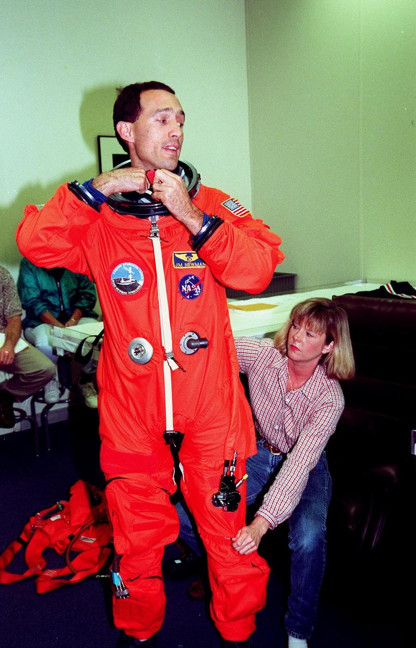 STS-88 Mission Specialist James H. Newman (left) suits up in the Operations and Checkout Building, as part of flight crew equipment fit check, prior to his trip to Launch Pad 39A. He is helped by suit tech Terri McKinney. The crew are at KSC to participate in the Terminal Countdown Demonstration Test (TCDT) which includes mission familiarization activities, emergency egress training, and the simulated main engine cut-off exercise. This is Newman's third space flight. Mission STS-88 is targeted for launch on Dec. 3, 1998. It is the first U.S. flight for the assembly of the International Space Station and will carry the Unity connecting module