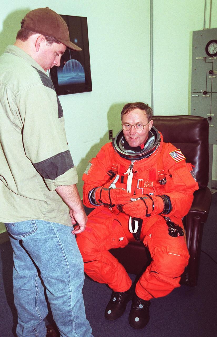 STS-88 Mission Specialist Jerry L. Ross (right) suits up in the Operations and Checkout Building, as part of a flight crew equipment fit check, prior to his trip to Launch Pad 39A. He is helped by suit tech Leonard Groce II. The STS-88 crew is at KSC to participate in the Terminal Countdown Demonstration Test (TCDT) which includes mission familiarization activities, emergency egress training, and a simulated launch countdown. This is Ross' sixth space flight. Mission STS-88 is targeted for launch on Dec. 3, 1998. It is the first U.S. flight for the assembly of the International Space Station and will carry the Unity connecting module