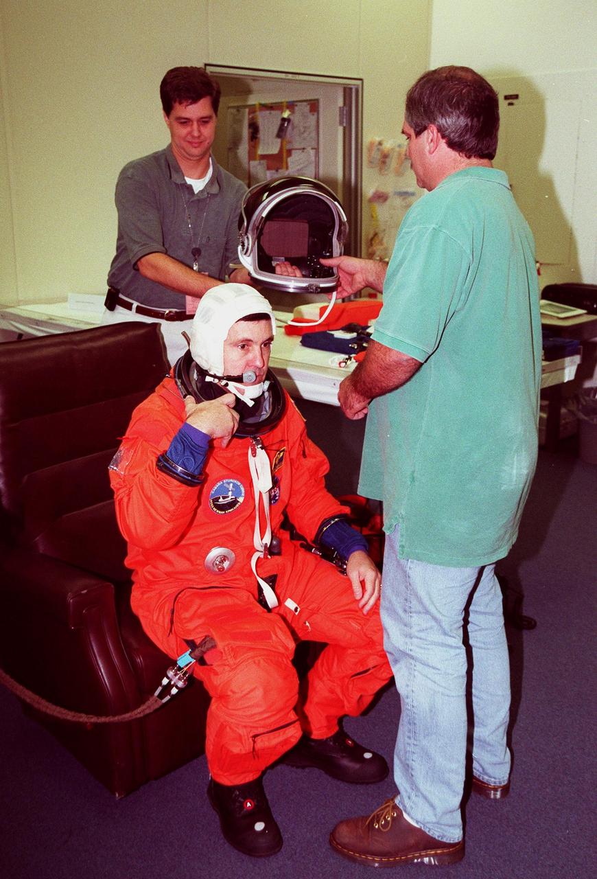 STS-88 Mission Commander Robert D. Cabana suits up in the Operations and Checkout Building prior, as part of flight crew equipment fit check, to his trip to Launch Pad 39A. He is helped by suit tech (right) Lloyd Armintor and an unidentified KSC worker. The crew are at KSC to participate in the Terminal Countdown Demonstration Test (TCDT) which includes mission familiarization activities, emergency egress training, and the simulated main engine cut-off exercise. This is Cabana's fourth space flight. Mission STS-88 is targeted for launch on Dec. 3, 1998. It is the first U.S. flight for the assembly of the International Space Station and will carry the Unity connecting module
