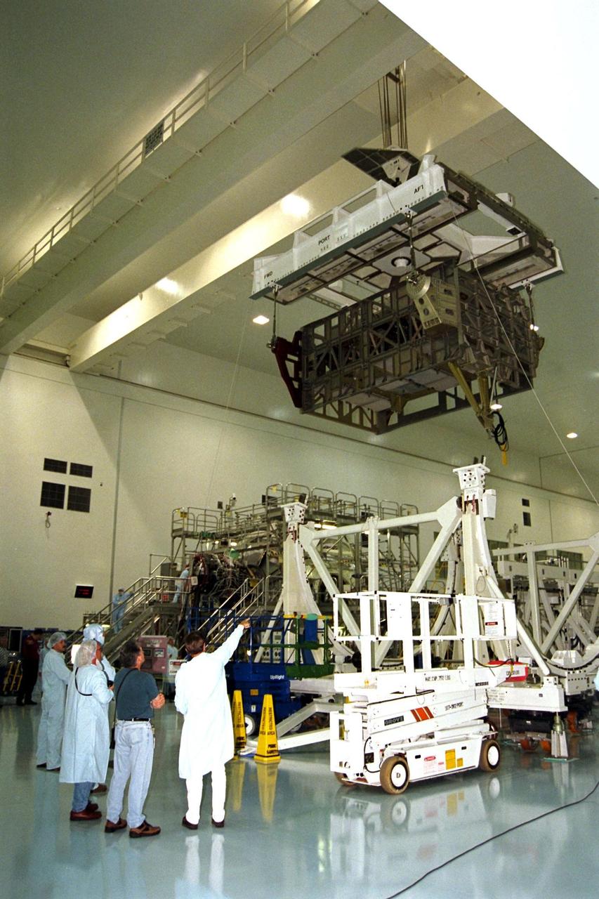 Workers in Kennedy Space Center’s Space Station Processing Facility (SSPF) observe the Photovoltaic Module 1 Integrated Equipment Assembly (IEA) as it moves past them on its way to its workstand, where it will be processed for flight on STS-97, scheduled for launch in April 1999. The IEA is one of four integral units designed to generate, distribute, and store power for the International Space Station. It will carry solar arrays, power storage batteries, power control units, and a thermal control system. The 16-foot-long, 16,850-pound unit is now undergoing preflight preparations in the SSPF