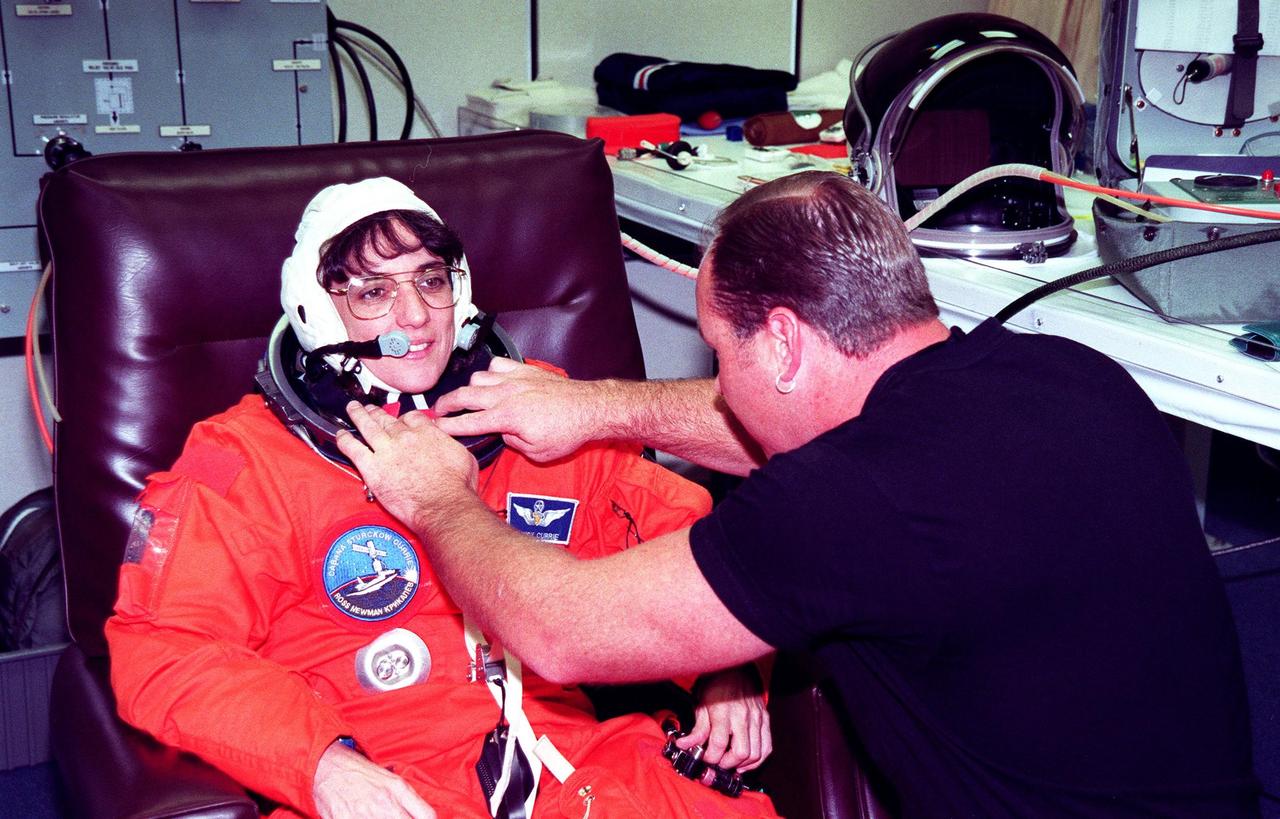 STS-88 Mission Specialist Nancy J. Currie suits up in the Operations and Checkout Building, as part of flight crew equipment fit check, prior to her trip to Launch Pad 39A. She is helped by suit tech Drew Billingsley. The crew are at KSC to participate in the Terminal Countdown Demonstration Test (TCDT) which includes mission familiarization activities, emergency egress training, and the simulated main engine cut-off exercise. This is Currie's third space flight. Mission STS-88 is targeted for launch on Dec. 3, 1998. It is the first U.S. flight for the assembly of the International Space Station and will carry the Unity connecting module