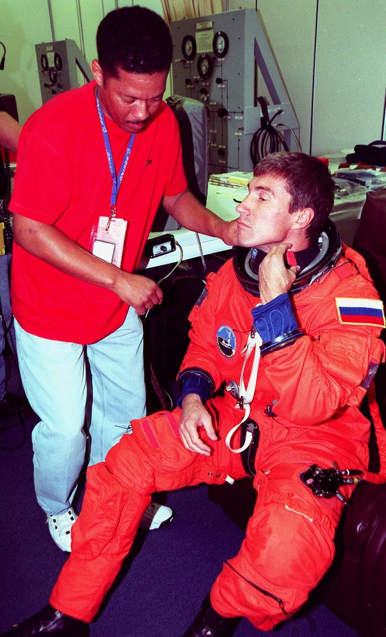 STS-88 Mission Specialist Sergei Konstantinovich Krikalev, a Russian cosmonaut, suits up in the Operations and Checkout Building, as part of a flight crew equipment fit check, prior to his trip to Launch Pad 39A. He is helped by suit tech George Brittingham. The STS-88 crew is at KSC to participate in the Terminal Countdown Demonstration Test (TCDT) which includes mission familiarization activities, emergency egress training, and a simulated launch countdown. This is Krikalev's second flight on the Space Shuttle. Mission STS-88 is targeted for launch on Dec. 3, 1998. It is the first U.S. flight for the assembly of the International Space Station and will carry the Unity connecting module