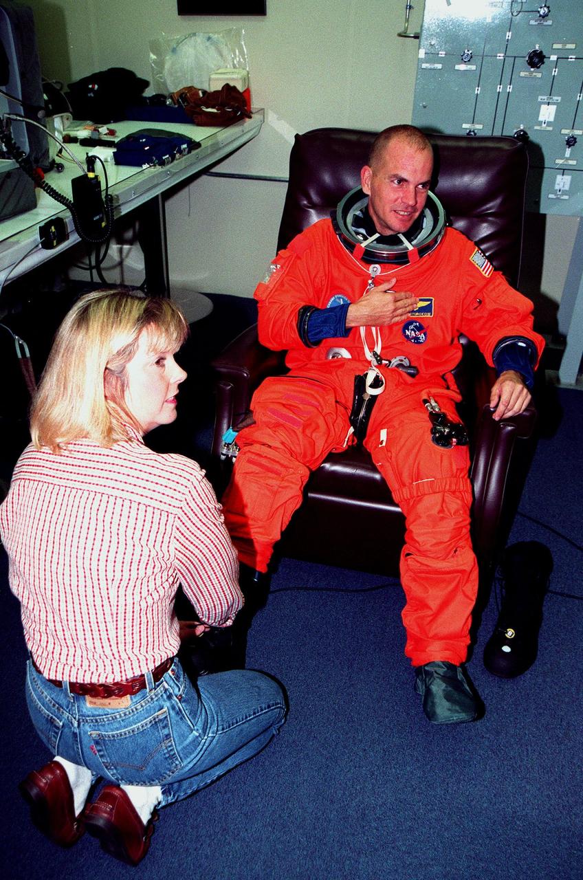 STS-88 Pilot Frederick W. "Rick" Sturckow suits up in the Operations and Checkout Building, as part of flight crew equipment fit check, prior to his trip to Launch Pad 39A. He is helped by suit tech Terri McKinney. The crew are at KSC to participate in the Terminal Countdown Demonstration Test (TCDT) which includes mission familiarization activities, emergency egress training, and the simulated main engine cut-off exercise. This is Sturckow's first space flight. Mission STS-88 is targeted for launch on Dec. 3, 1998. It is the first U.S. flight for the assembly of the International Space Station and will carry the Unity connecting module