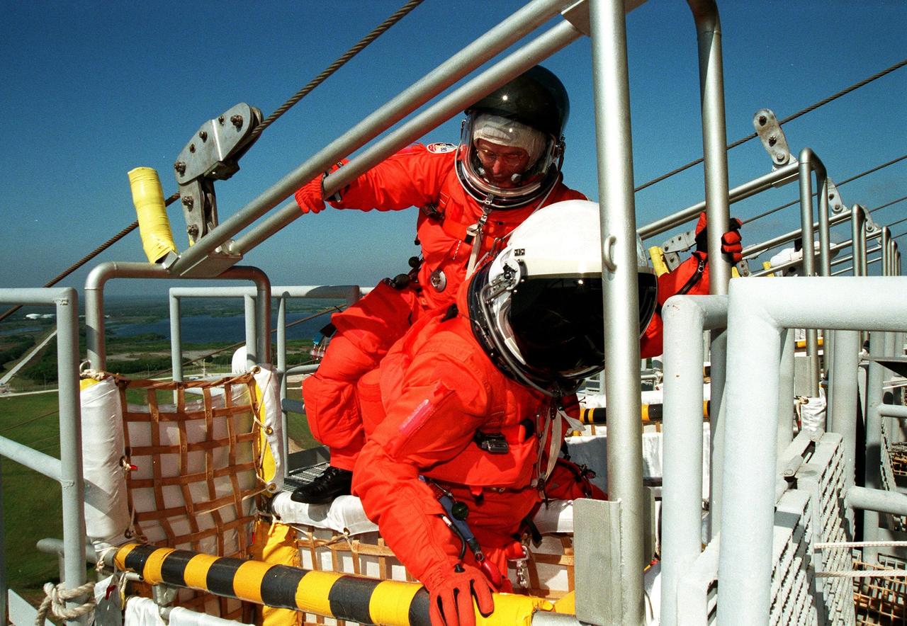 KENNEDY SPACE CENTER, Fla. --  STS-88 Mission Specialist Jerry L. Ross (left) climbs into slideware basket behind Mission Specialist Nancy Jane Currie, Ph.D., (right) at Launch Pad 39A as part of an emergency egress exercise. The crew are at KSC to participate in the Terminal Countdown Demonstration Test (TCDT) which includes mission familiarization activities, emergency egress training, and the simulated main engine cut-off exercise. Mission STS-88 is targeted for launch on Dec. 3, 1998. It is the first U.S. flight for the assembly of the International Space Station and will carry the Unity connecting module. Unity will be mated with the already orbiting Russian-built Zarya control module. The 12-day mission includes three planned spacewalks to connect power, data and utility lines and install exterior equipment
