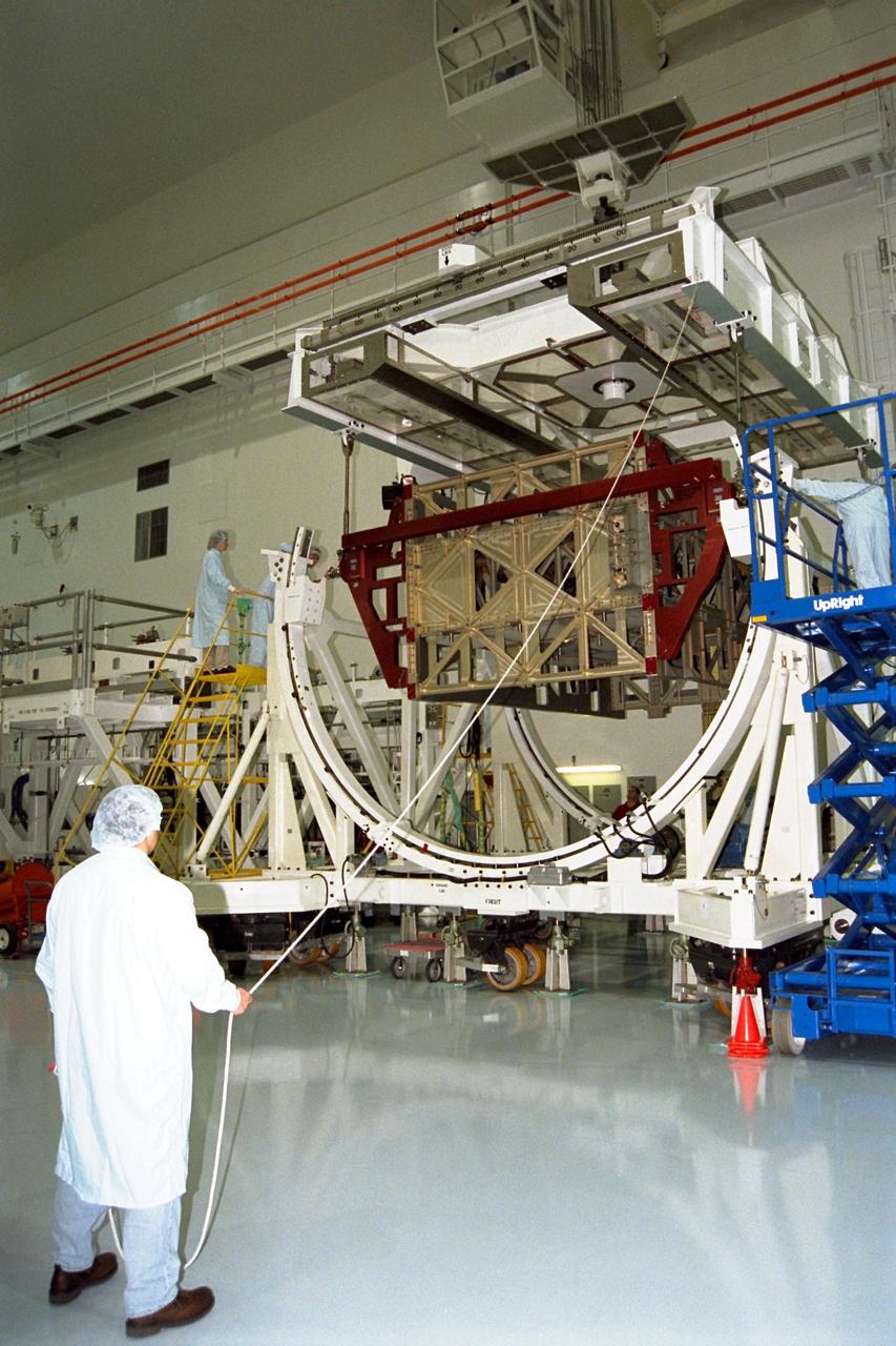 The Photovoltaic Module 1 Integrated Equipment Assembly (IEA) is lowered into its workstand at Kennedy Space Center’s Space Station Processing Facility (SSPF), where it will be processed for flight on STS-97, scheduled for launch in April 1999. The IEA is one of four integral units designed to generate, distribute, and store power for the International Space Station. It will carry solar arrays, power storage batteries, power control units, and a thermal control system. The 16-foot-long, 16,850-pound unit is now undergoing preflight preparations in the SSPF