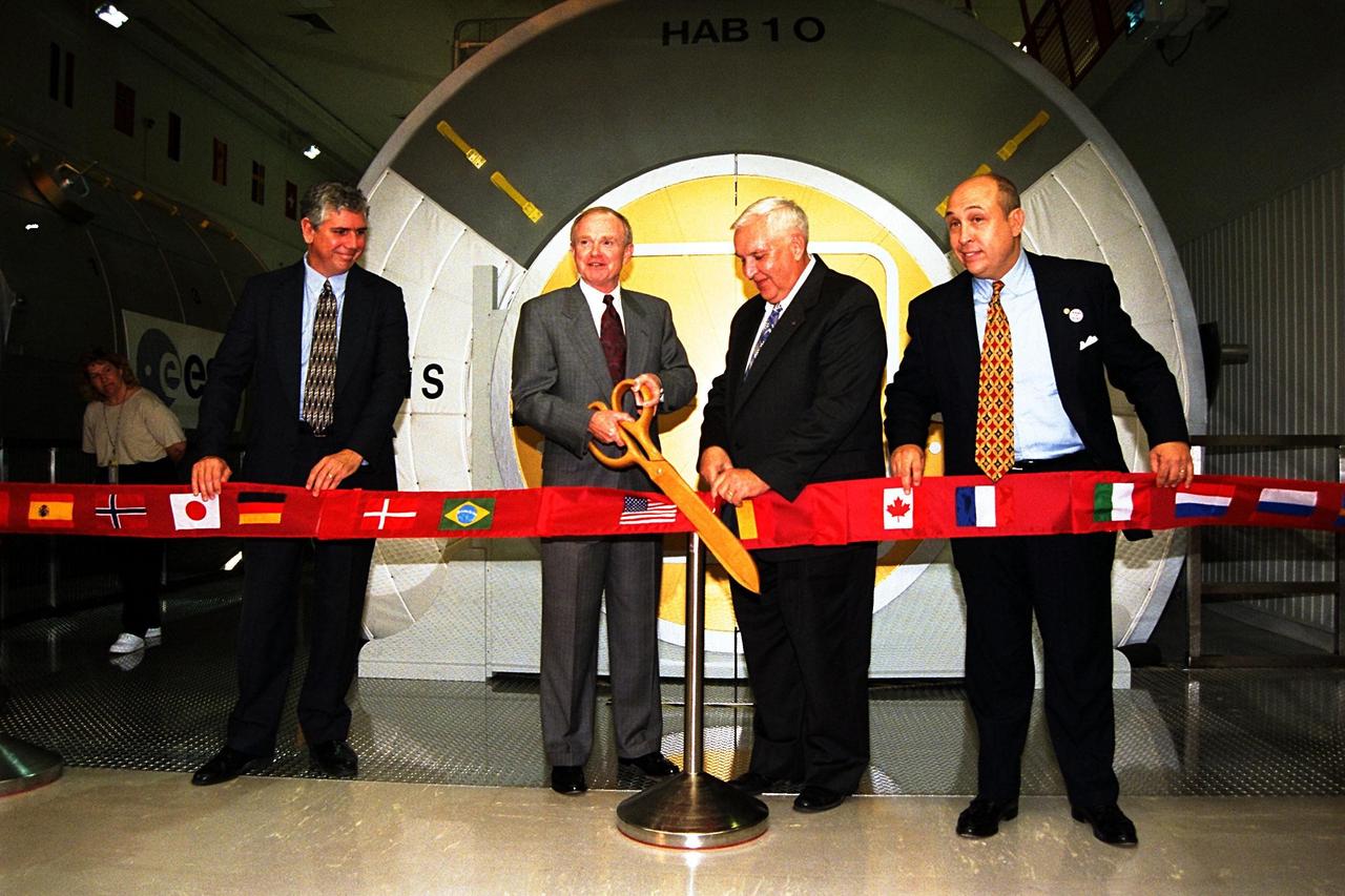 Celebrating the official opening of the new International Space Station (ISS) Center at Kennedy Space Center are, left to right, James Ball, chief, NASA Public Services, KSC; KSC Director Roy D. Bridges Jr.; Hugh Harris, director, NASA Public Affairs, KSC; and Rick Abramson, president and chief operating officer, Delaware North Parks Services of Spaceport Inc. Center Director Bridges cuts the ribbon to the new tour attraction where full-scale mockups of station modules, through which visitors can walk, are on display. These include the Habitation Unit, where station crew members will live, sleep, and work; a Laboratory Module; and the Pressurized Logistics Module, where racks and supplies will be transported back and forth from KSC to space. Guests also can take an elevated walkway to a gallery overlooking the work are where actual ISS hardware is prepared for flight into space. This new tour site, in addition to a new Launch Complex 39 Observation Gantry, are part of a comprehensive effort by NASA and Delaware North to expand and improve the KSC public tour and visitor facilities