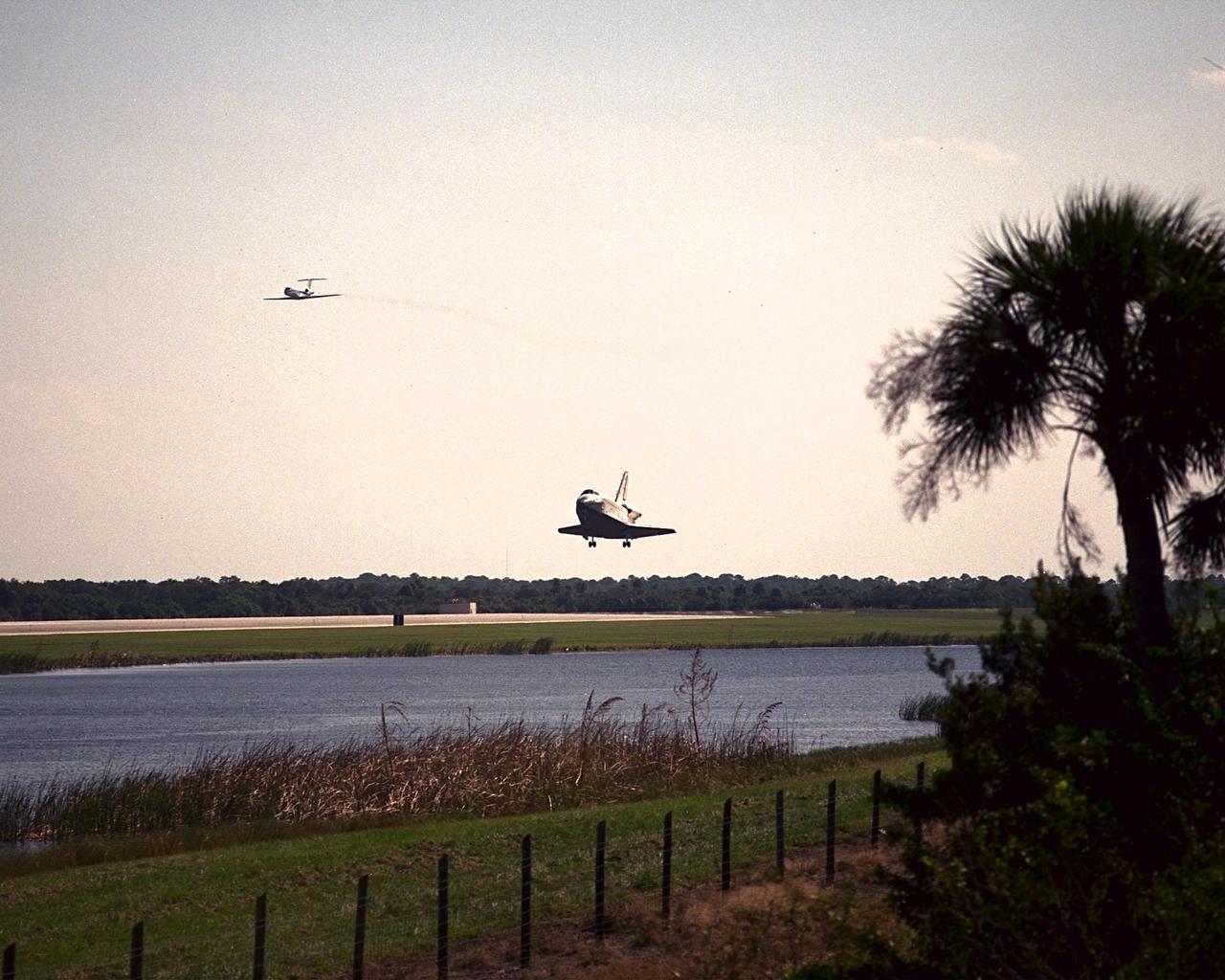 KENNEDY SPACE CENTER, FLA. -- Seen from across the creek bordering runway 33 at the Shuttle Landing Facility, orbiter Discovery touches down after a successful mission of nine days and 3.6 million miles. Flying above it (left) is the Shuttle Training Aircraft. Main gear touchdown was at 12:04 p.m. EST, landing on orbit 135. The STS-95 crew consists of Mission Commander Curtis L. Brown Jr.; Pilot Steven W. Lindsey; Mission Specialist Scott E. Parazynski; Mission Specialist Stephen K. Robinson; Payload Specialist John H. Glenn Jr., senator from Ohio; Mission Specialist Pedro Duque, with the European Space Agency (ESA); and Payload Specialist Chiaki Mukai, with the National Space Development Agency of Japan (NASDA). The mission included research payloads such as the Spartan solar-observing deployable spacecraft, the Hubble Space Telescope Orbital Systems Test Platform, the International Extreme Ultraviolet Hitchhiker, as well as the SPACEHAB single module with experiments on space flight and the aging process