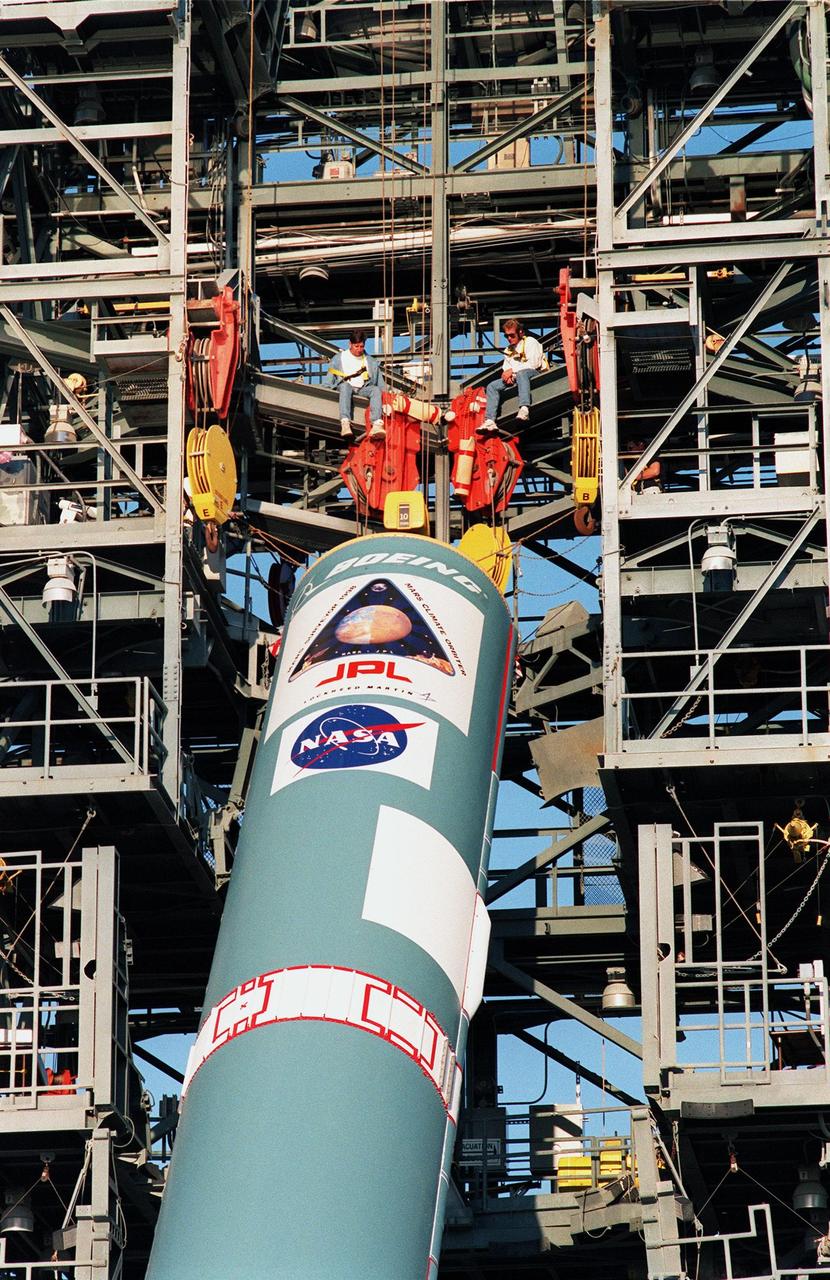 KENNEDY SPACE CENTER, FLA. -- On Pad 17A at Cape Canaveral Air Station, workers on the gantry watch as cables lift a Delta II rocket into position for launch. Scheduled for launch on Dec. 10, 1998, the rocket is carrying the Mars Climate Orbiter. The orbiter is heading for Mars where it will primarily support its companion Mars Polar Lander spacecraft, which is planned for launch on Jan. 3, 1999. The orbiter's instruments will monitor the Martian atmosphere and image the planet's surface on a daily basis for one Martian year (1.8 Earth years). It will observe the appearance and movement of atmospheric dust and water vapor, as well as characterize seasonal changes on the surface. The detailed images of the surface features will provide important clues to the planet's early climate history and give scientists more information about possible liquid water reserves beneath the surface