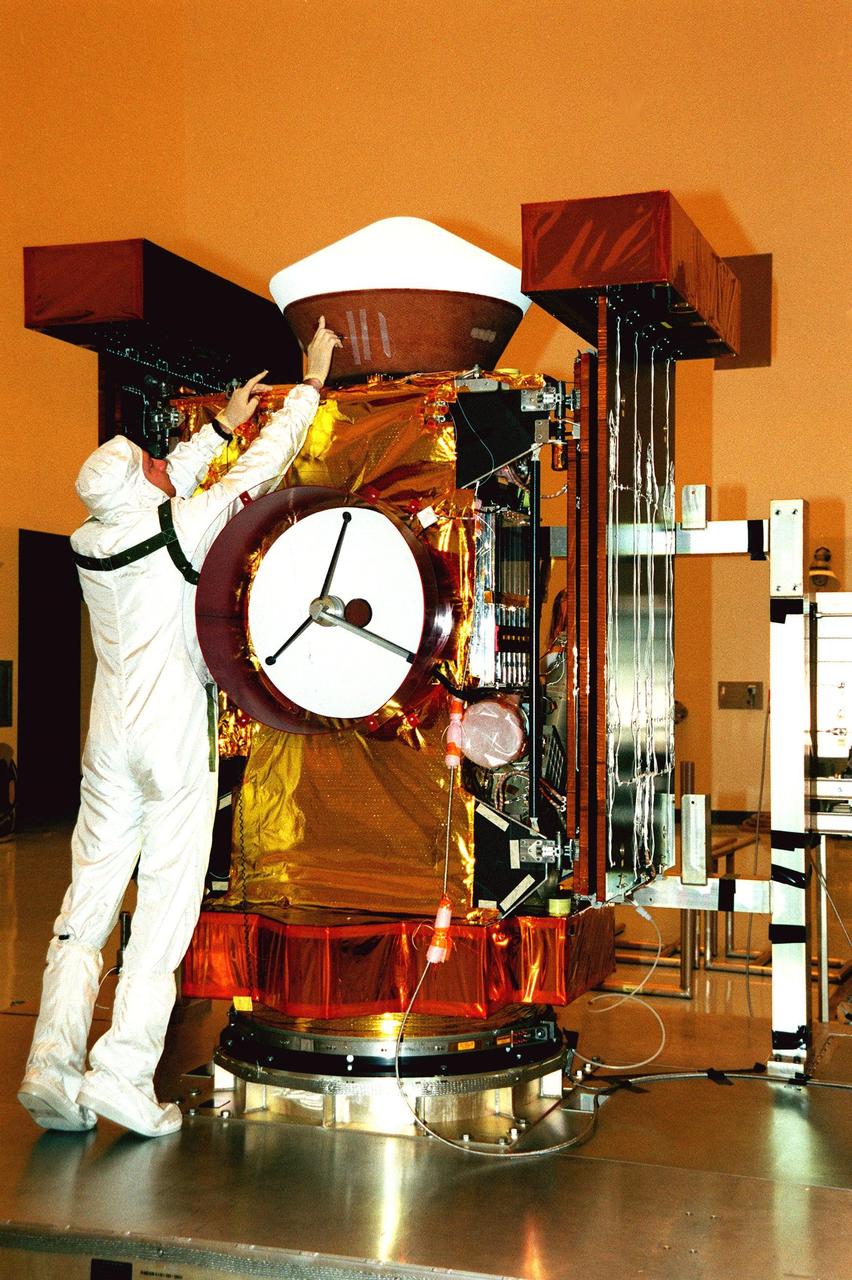 In the Payload Hazardous Service Facility, a worker looks over the re-entry capsule on top of the Stardust spacecraft. The spacecraft will undergo installation and testing of the solar arrays, plus final installation and testing of spacecraft instruments followed by an overall spacecraft functional test. Built by Lockheed Martin Astronautics near Denver, Colo., for the Jet Propulsion Laboratory (JPL) and NASA, the spacecraft Stardust will use a unique medium called aerogel to capture comet particles flying off the nucleus of comet Wild 2 in January 2004, plus collect interstellar dust for later analysis. Stardust will be launched aboard a Boeing Delta 7426 rocket from Complex 17, Cape Canaveral Air Station, targeted for Feb. 6, 1999. The collected samples will return to Earth in the re-entry capsule to be jettisoned from Stardust as it swings by Earth in January 2006