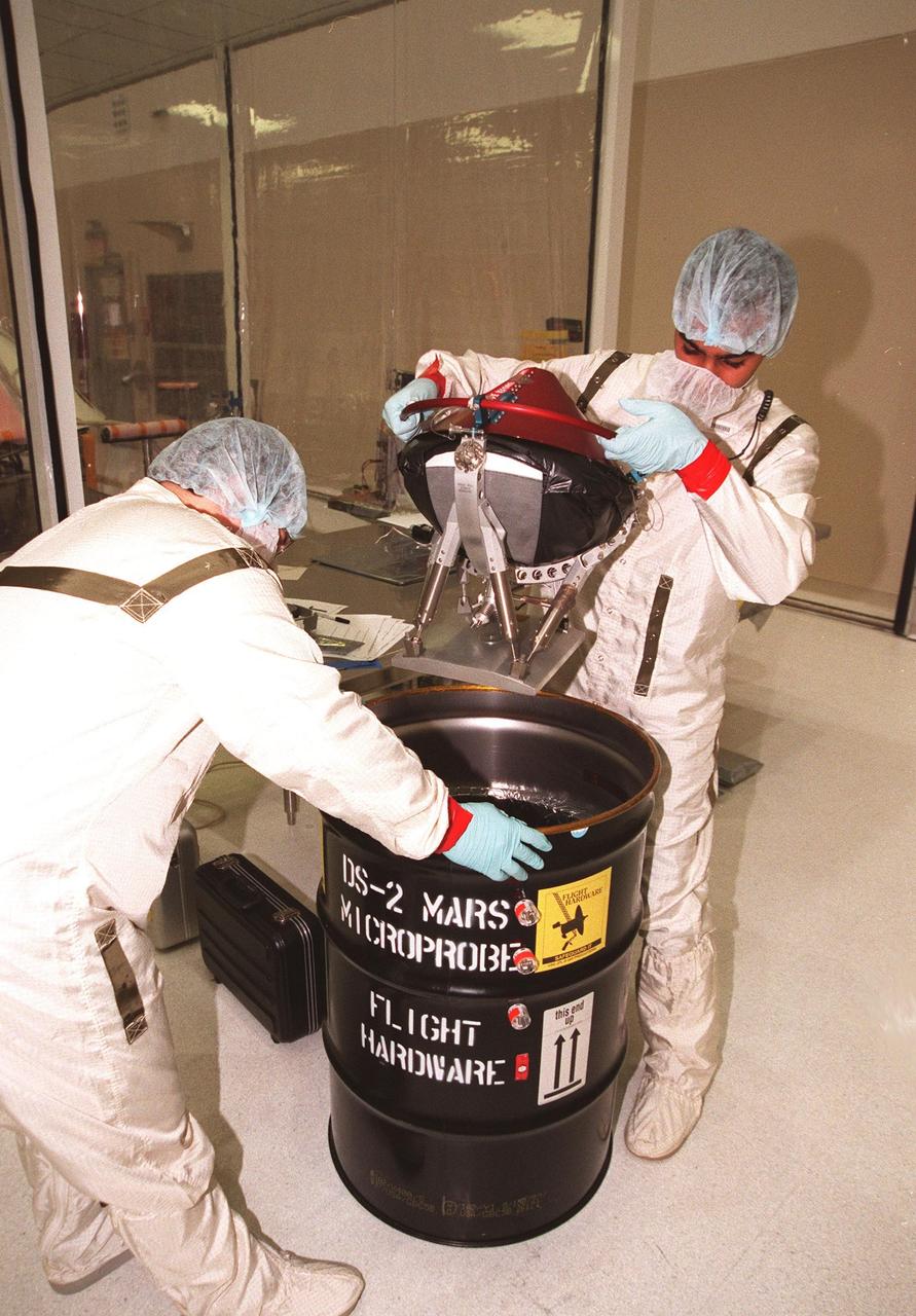 KENNEDY SPACE CENTER, FLA. -- In the Spacecraft Assembly and Encapsulation Facility -2 (SAEF-2), Chris Voorhees (left) and Satish Krishnan (right), from the Jet Propulsion Laboratory, remove the second Mars microprobe from a drum. Two microprobes will hitchhike on the Mars Polar Lander, scheduled to be launched Jan. 3, 1999, aboard a Delta II rocket. The solar-powered spacecraft is designed to touch down on the Martian surface near the northern-most boundary of the south pole in order to study the water cycle there. The lander also will help scientists learn more about climate change and current resources on Mars, studying such things as frost, dust, water vapor and condensates in the Martian atmosphere. The Mars microprobes, called Deep Space 2, are part of NASA's New Millennium Program. They will complement the climate-related scientific focus of the lander by demonstrating an advanced, rugged microlaser system for detecting subsurface water. Such data on polar subsurface water, in the form of ice, should help put limits on scientific projections for the global abundance of water on Mars